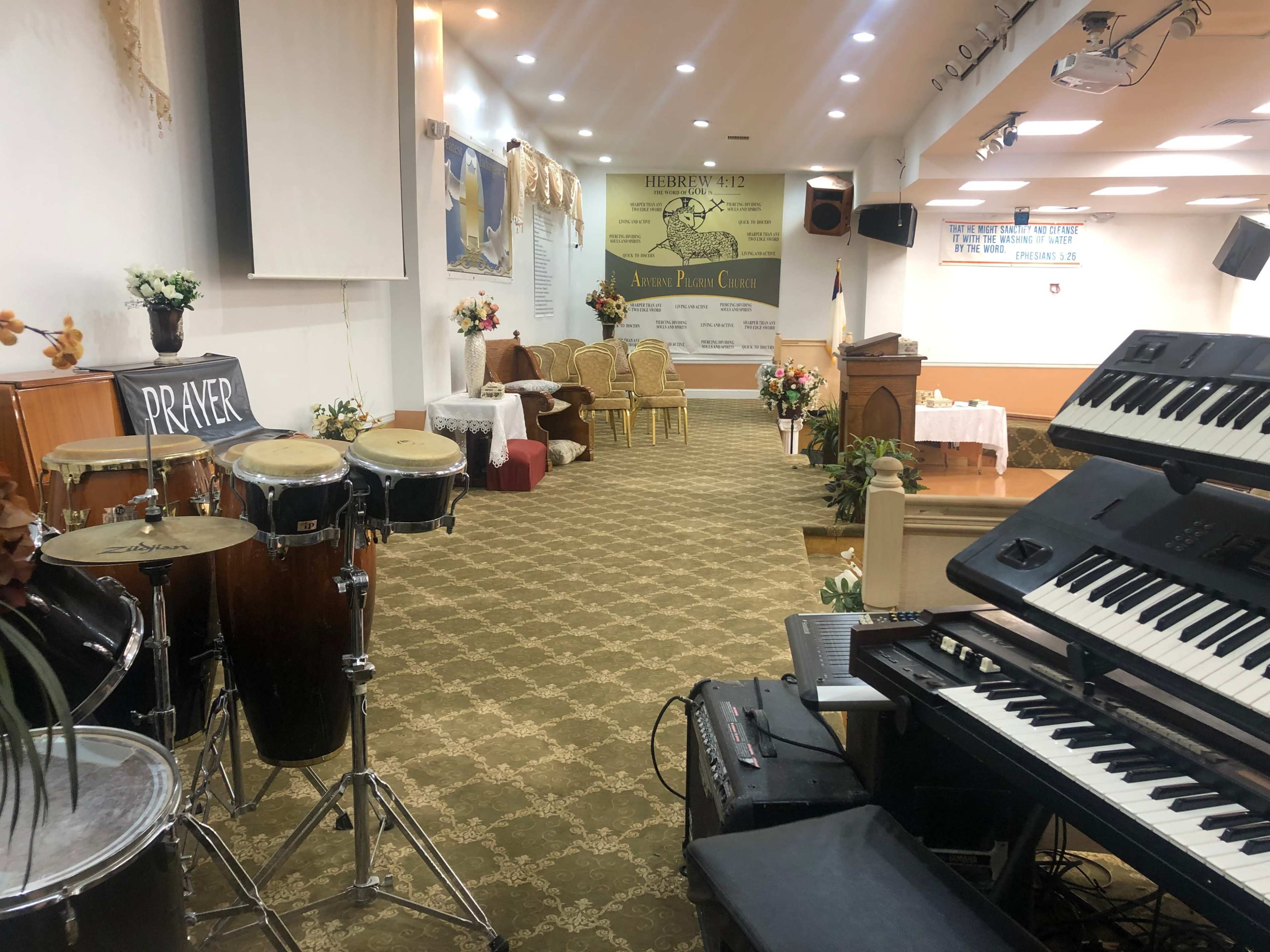 An interior of a church with musical instruments, a stage area, and decorative floral arrangements.