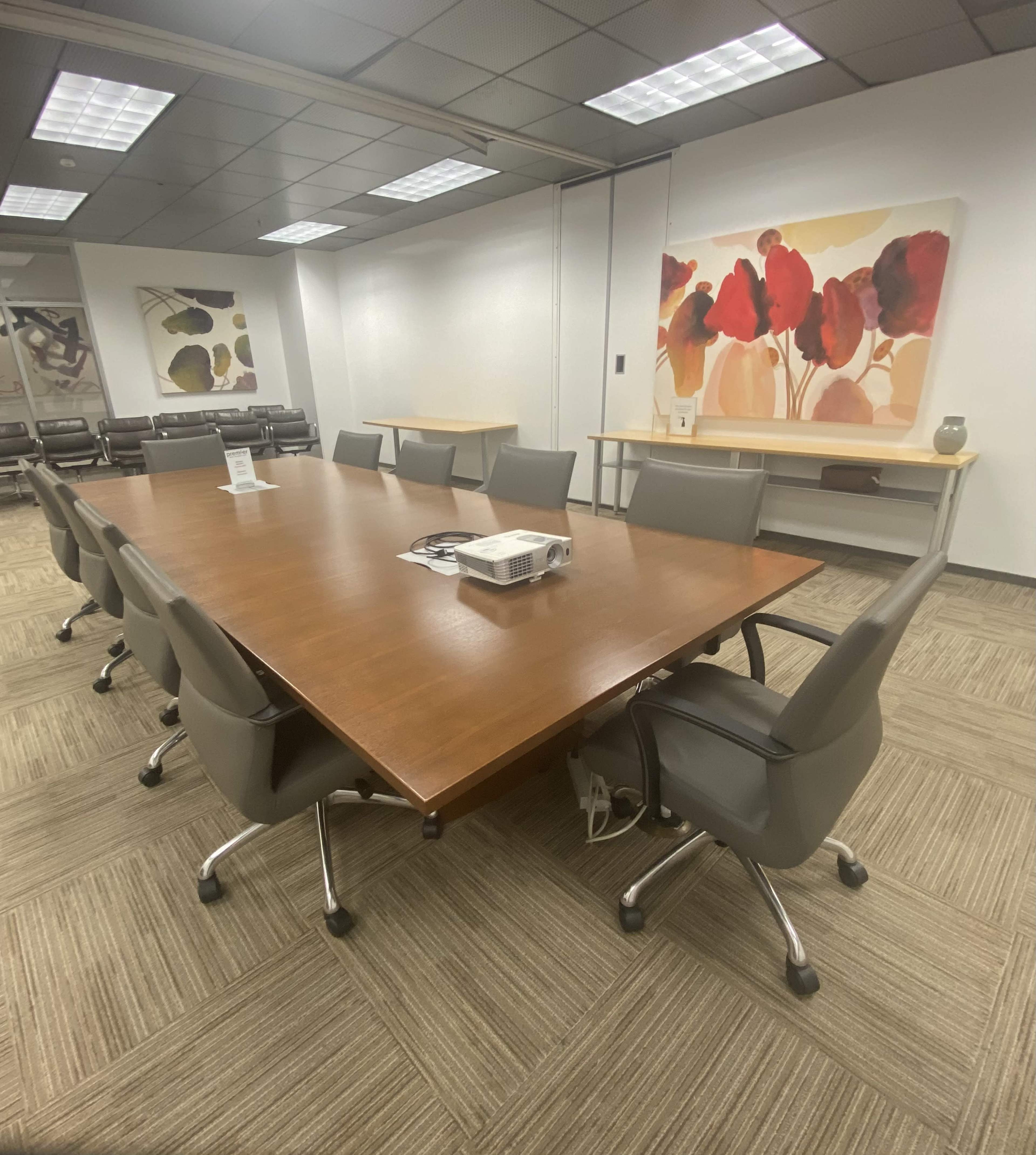 A large conference room features a wood table surrounded by ergonomic chairs, with abstract art displayed on the walls.