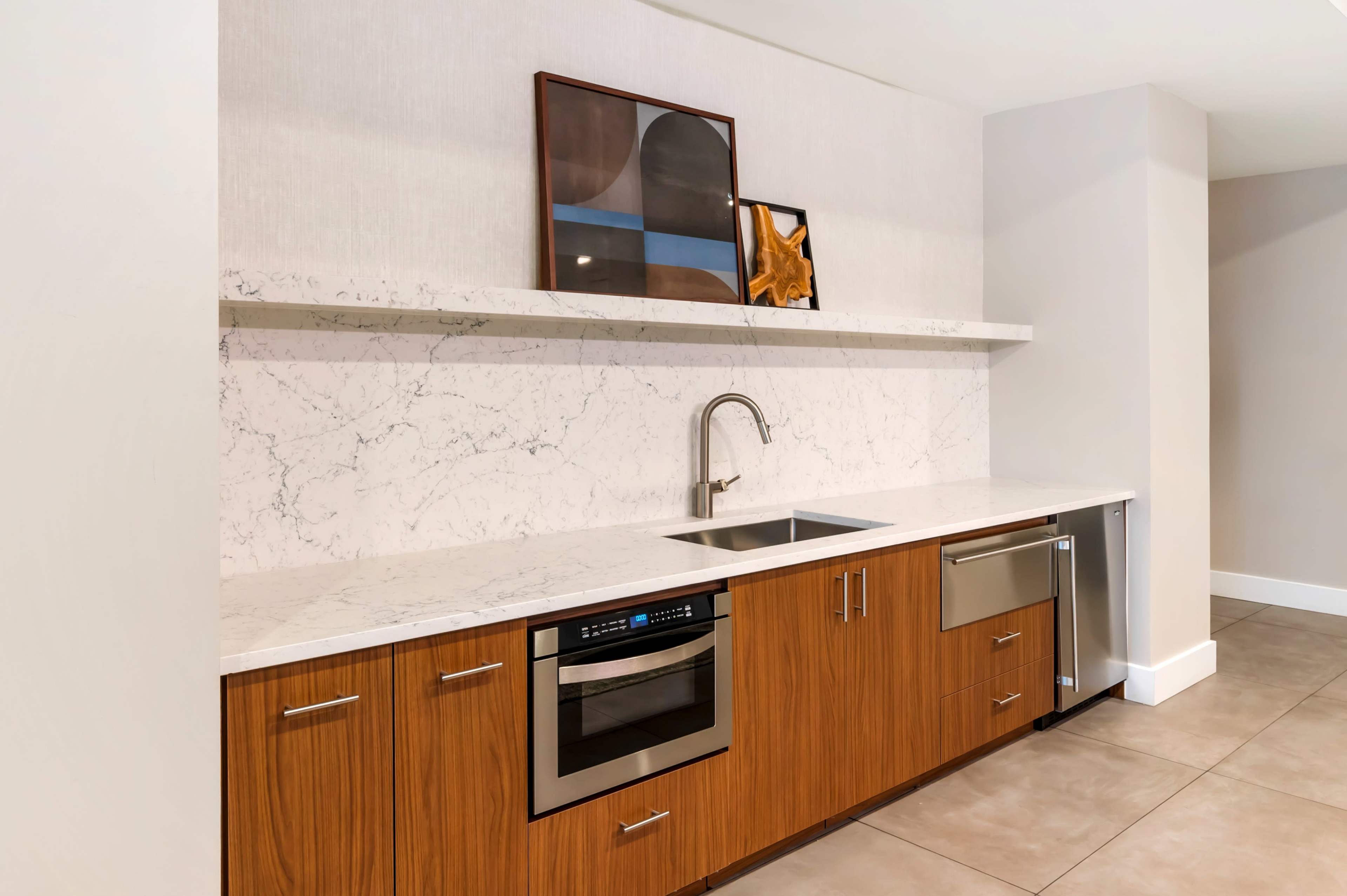 The image shows a modern kitchen with a marble countertop, stainless steel appliances, and wooden cabinetry.