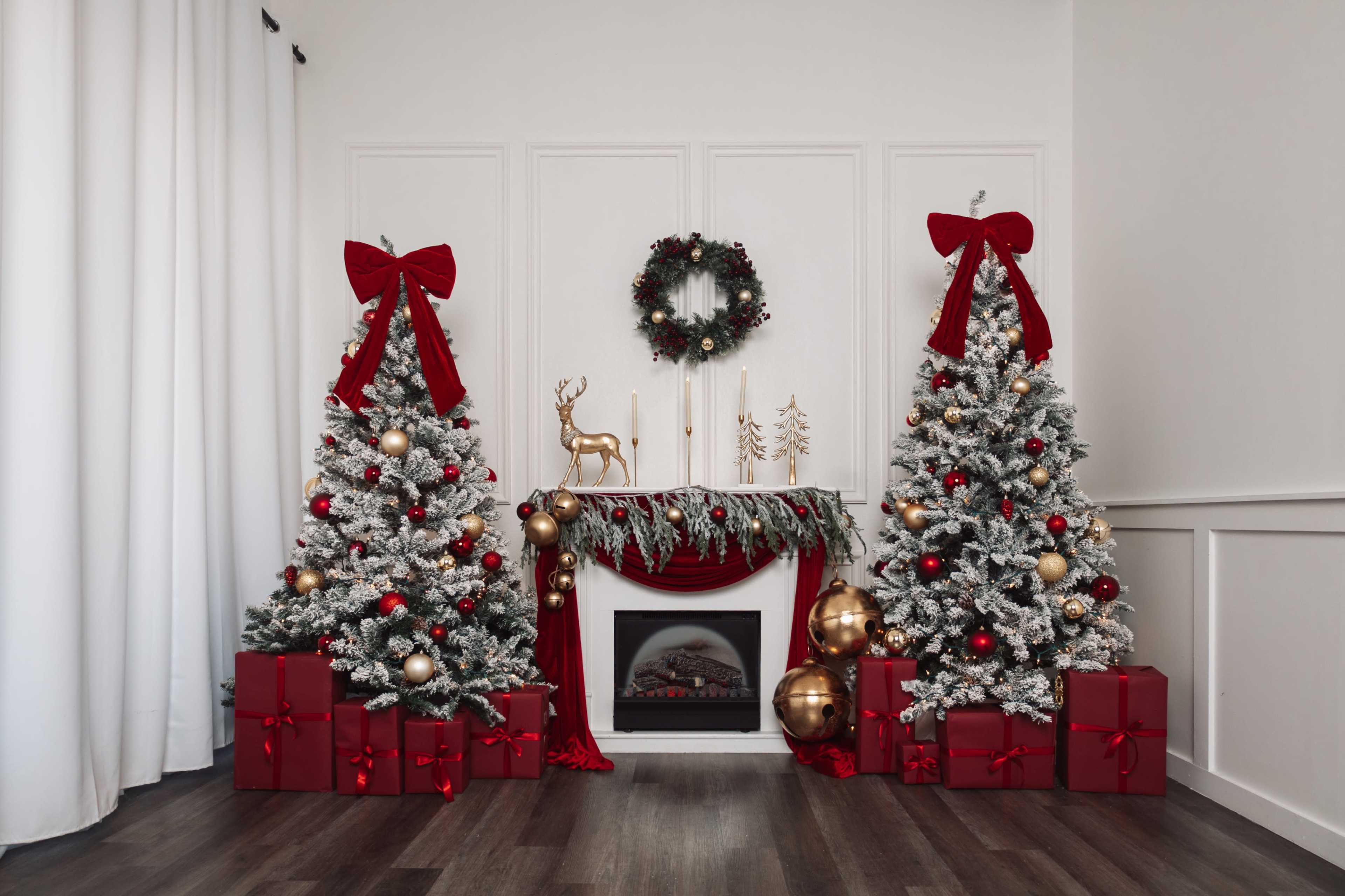 The image features a festive holiday scene with two decorated Christmas trees flanking a fireplace, adorned with red bows, garlands, and gold ornaments, along with wrapped presents beneath the trees.