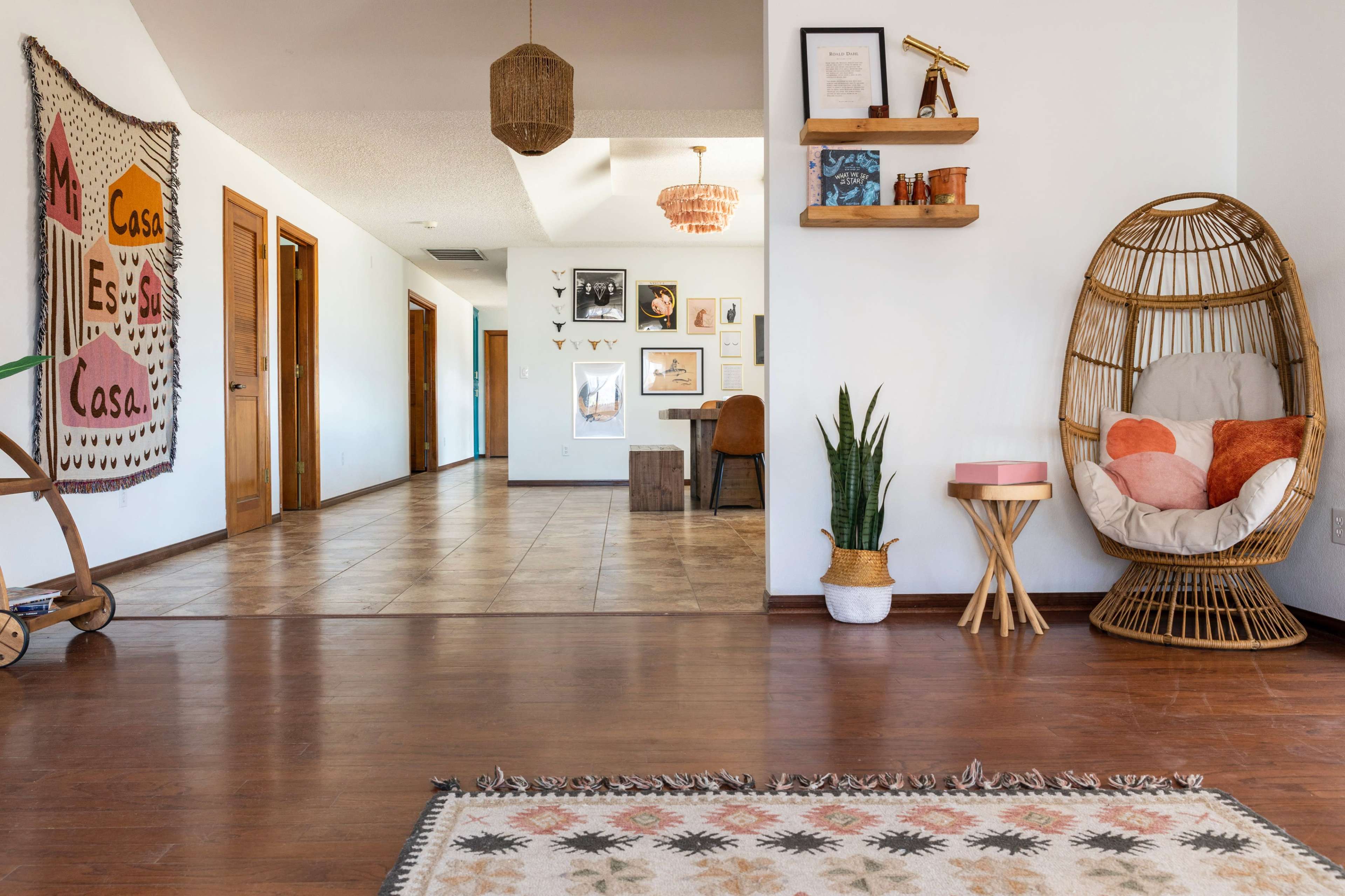 A modern interior space featuring a decorated wall, wooden doors, a comfortable chair, a small table, and various decorative elements.