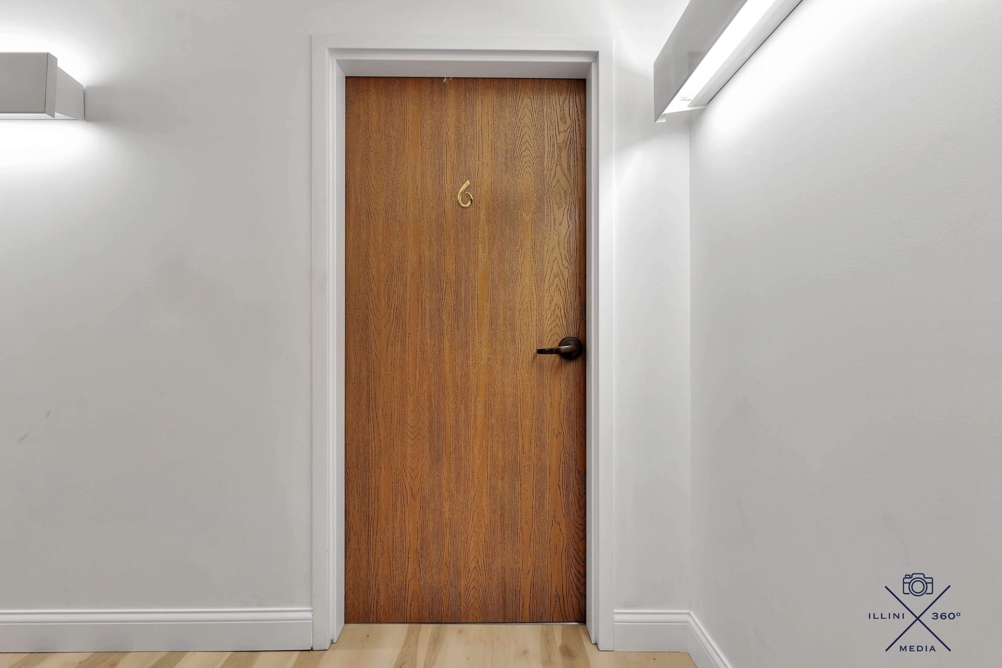 The image features a wooden door with a number 6 on it, set against a white wall and light-colored flooring.