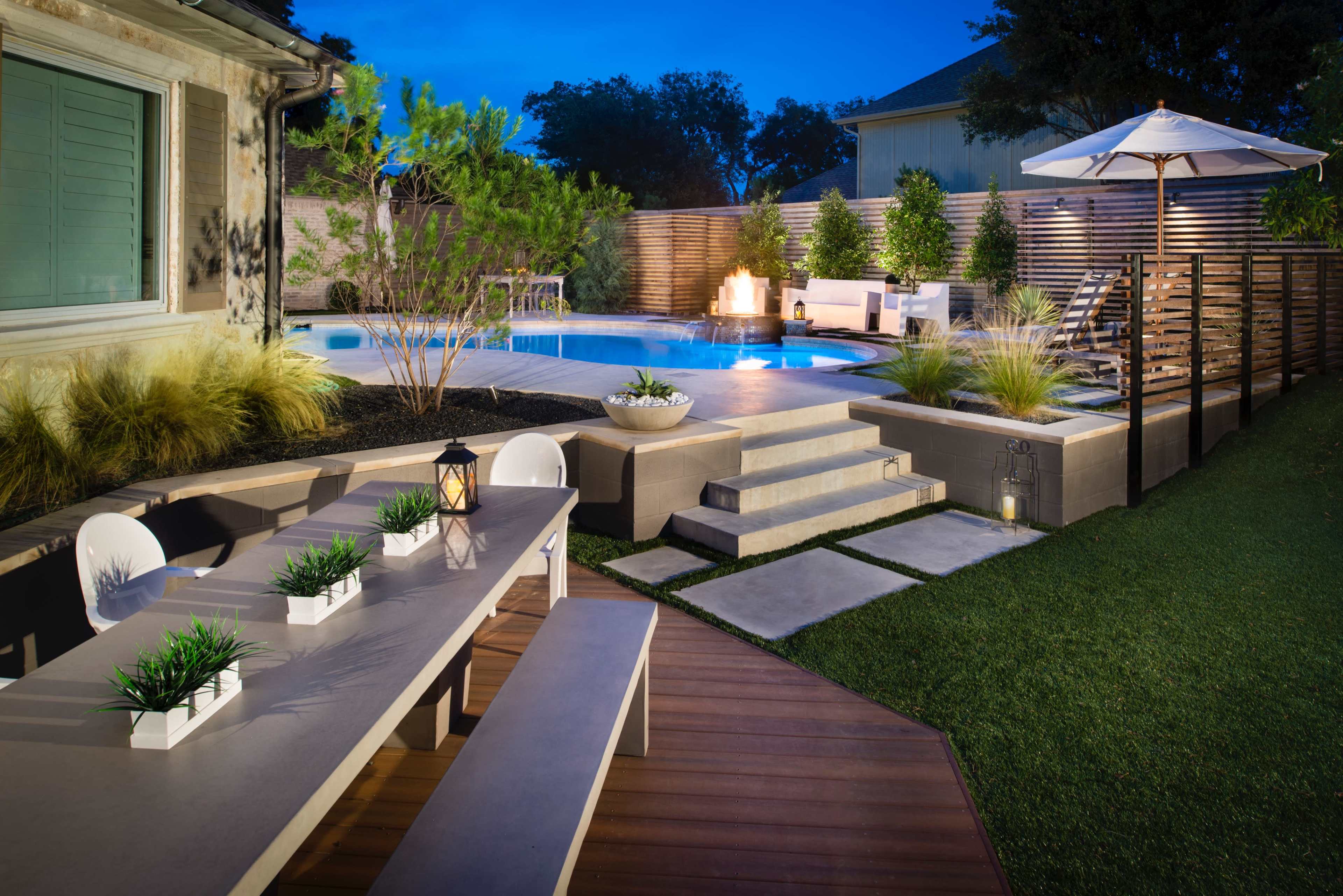 The image depicts a modern backyard featuring a swimming pool, elegant seating areas, and a dining table under soft lighting.