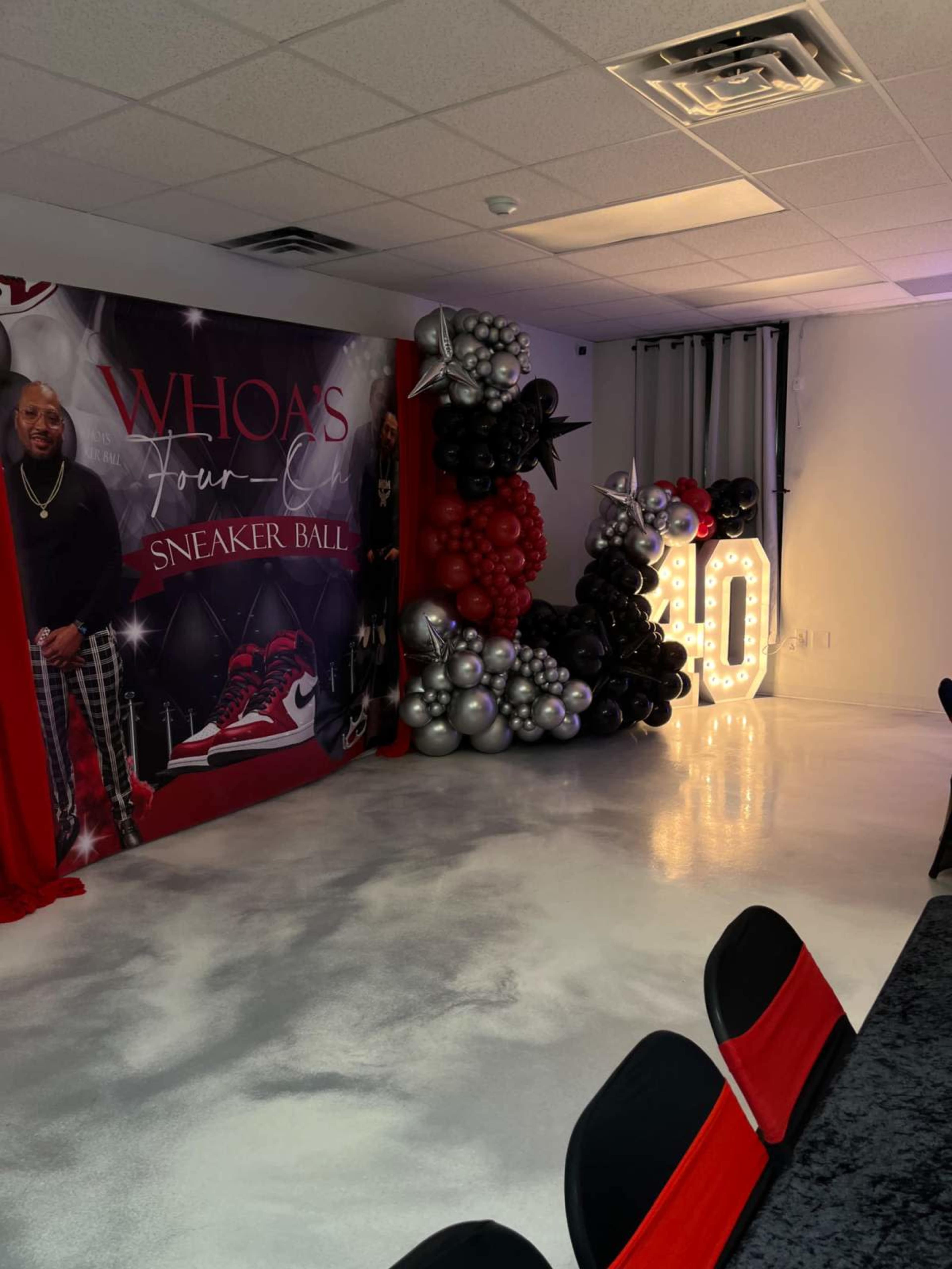 The room is decorated for a sneaker-themed ball, featuring a large balloon display, a "40" sign made of lights, and a photo backdrop.