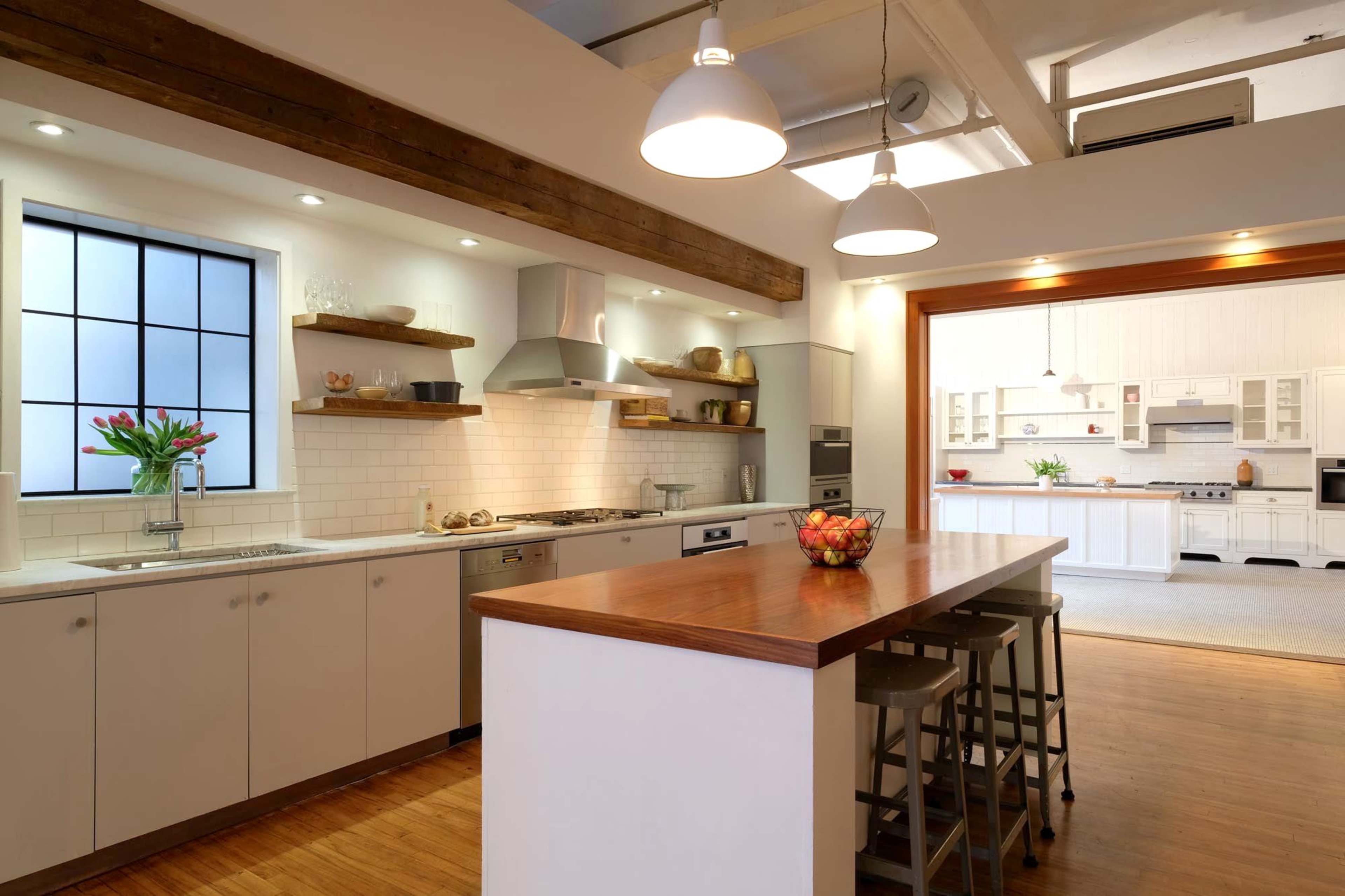 A modern kitchen with wooden shelves, stainless steel appliances, and an island with bar stools.