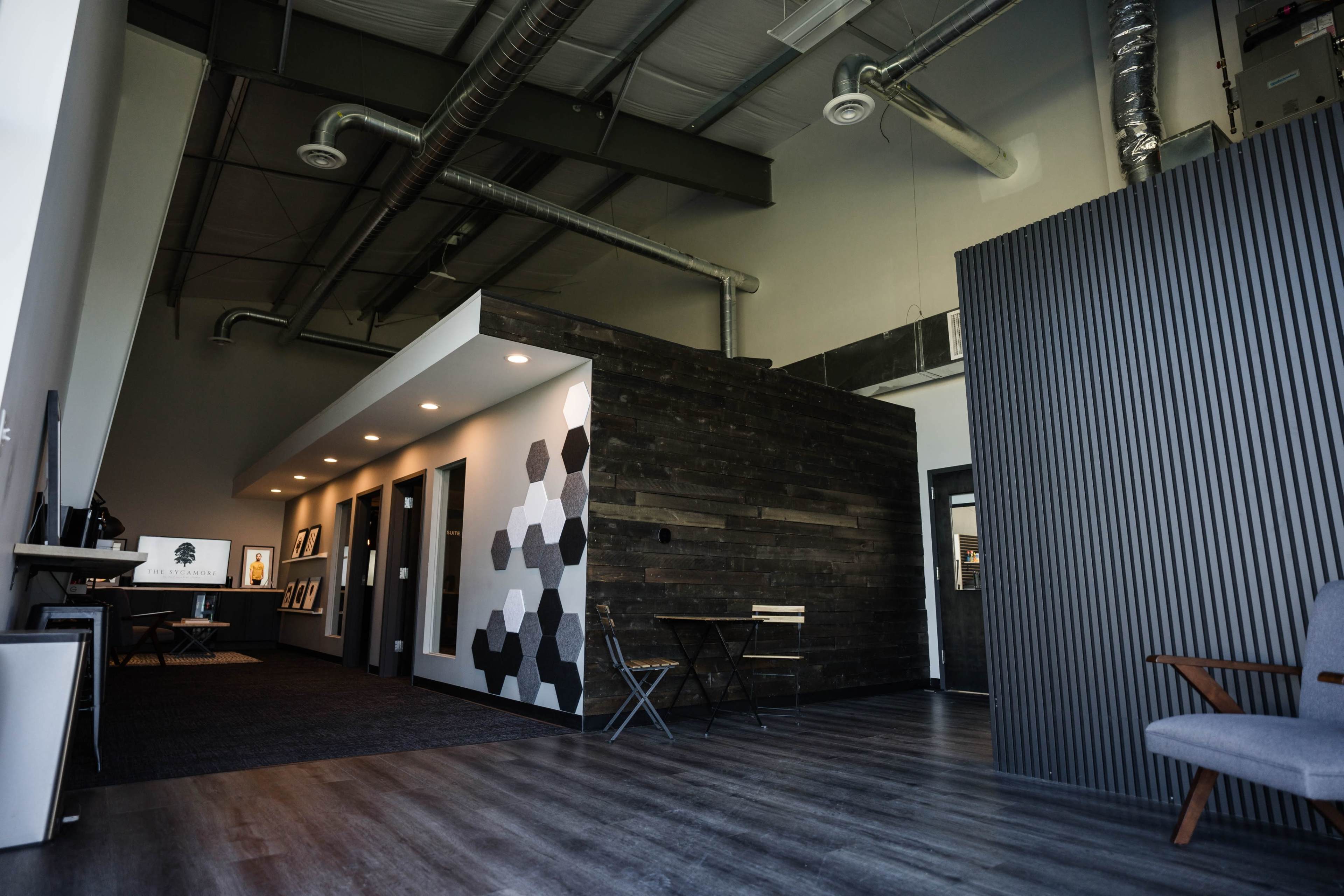 A modern office interior featuring a mix of wooden and patterned wall panels, a sleek reception area, and minimalist furniture.
