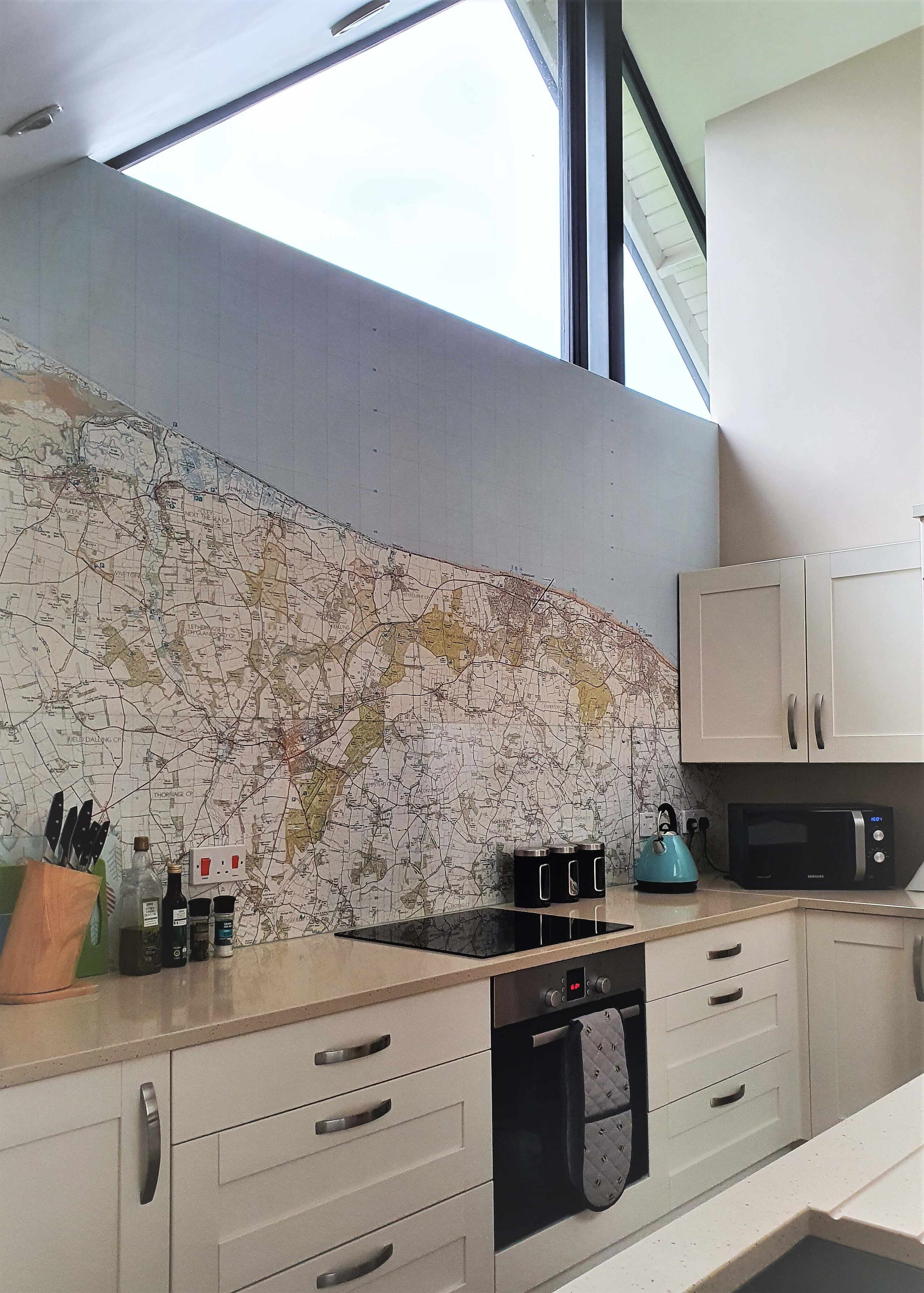The kitchen features a large wall mural of a detailed map, with modern cabinets and appliances arranged below it.