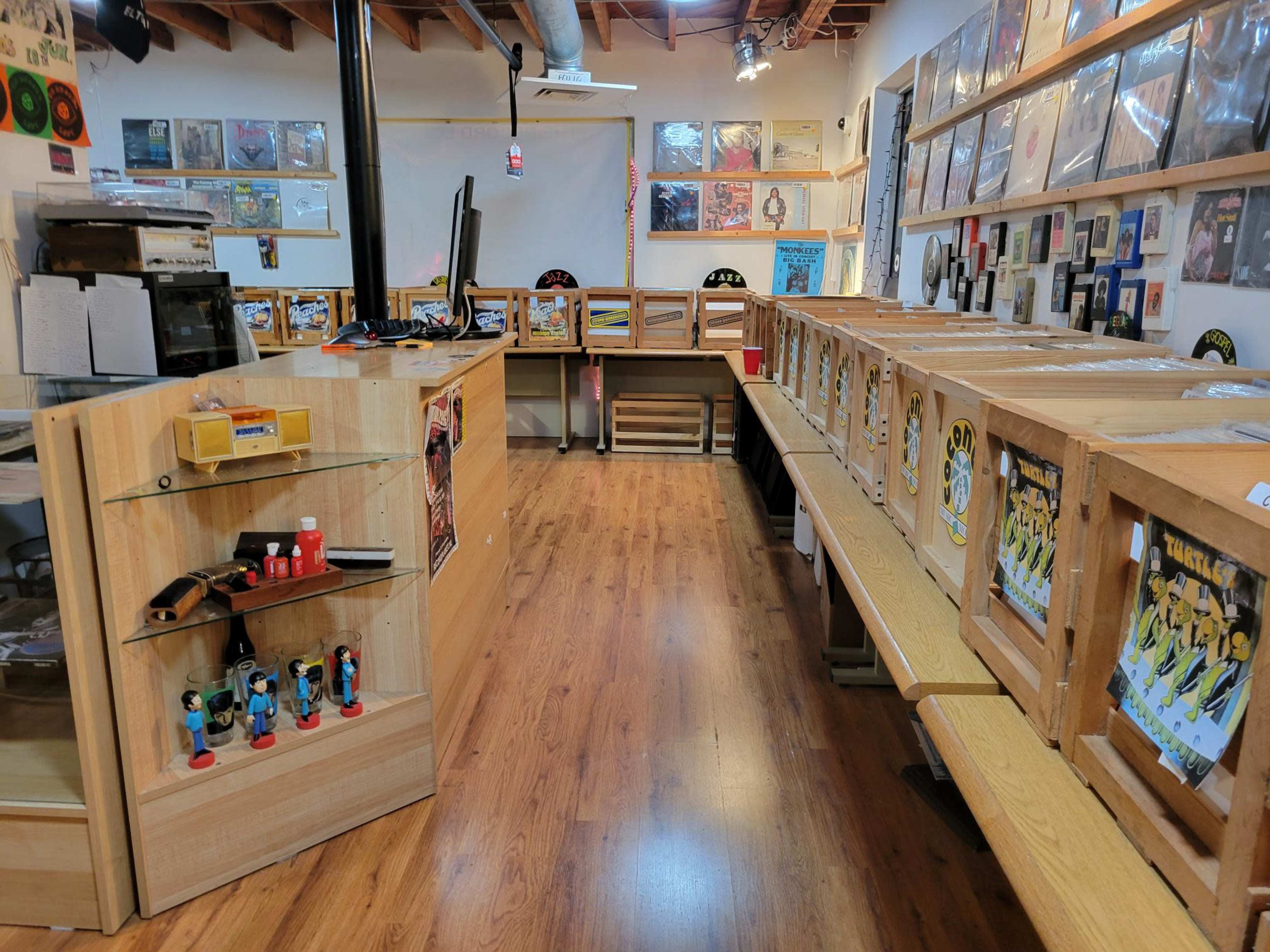 The interior of a vinyl record store, featuring wooden crates filled with records and display counters against the walls.