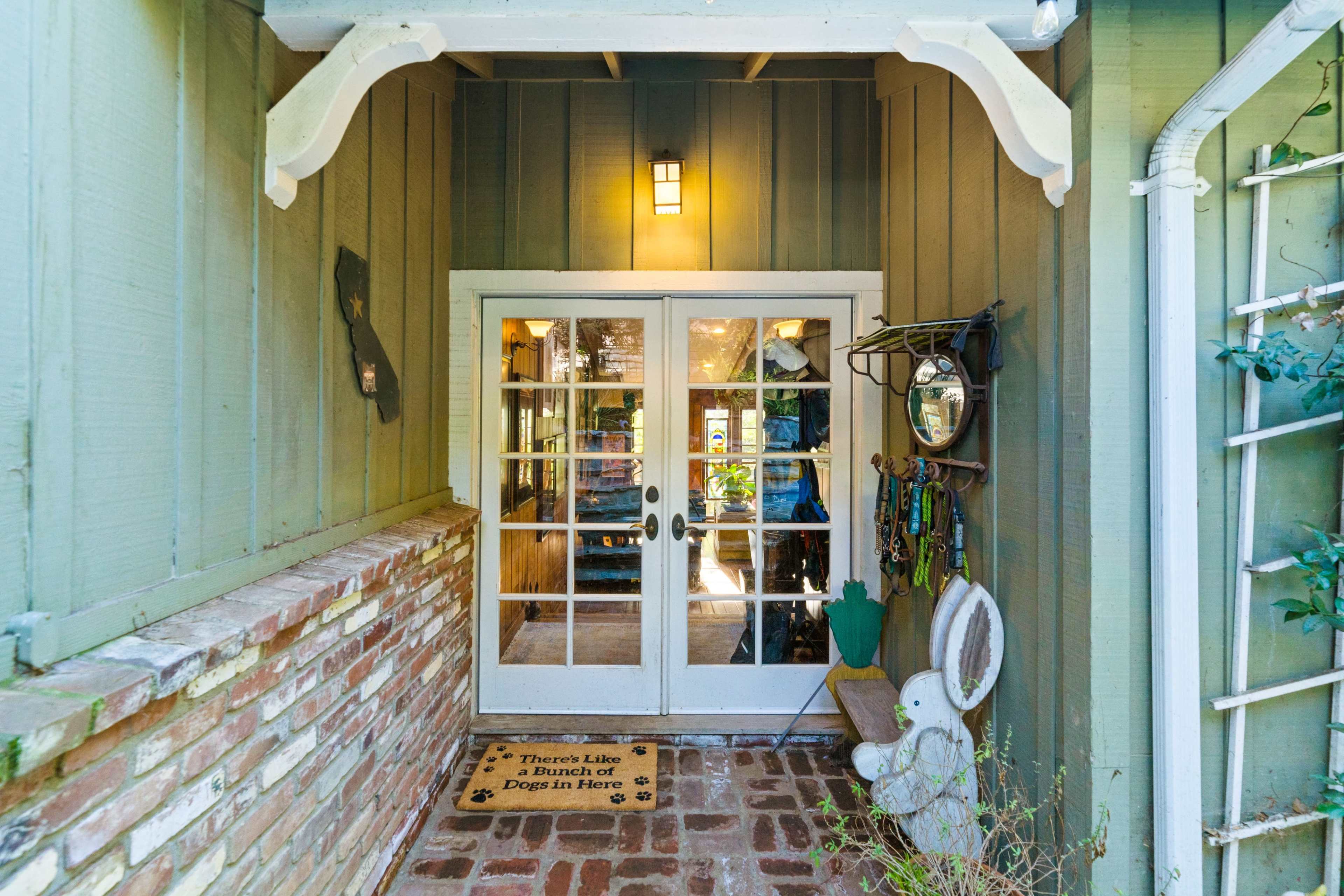 A welcoming entrance with double glass doors, a doormat, and decorative elements on the walls.