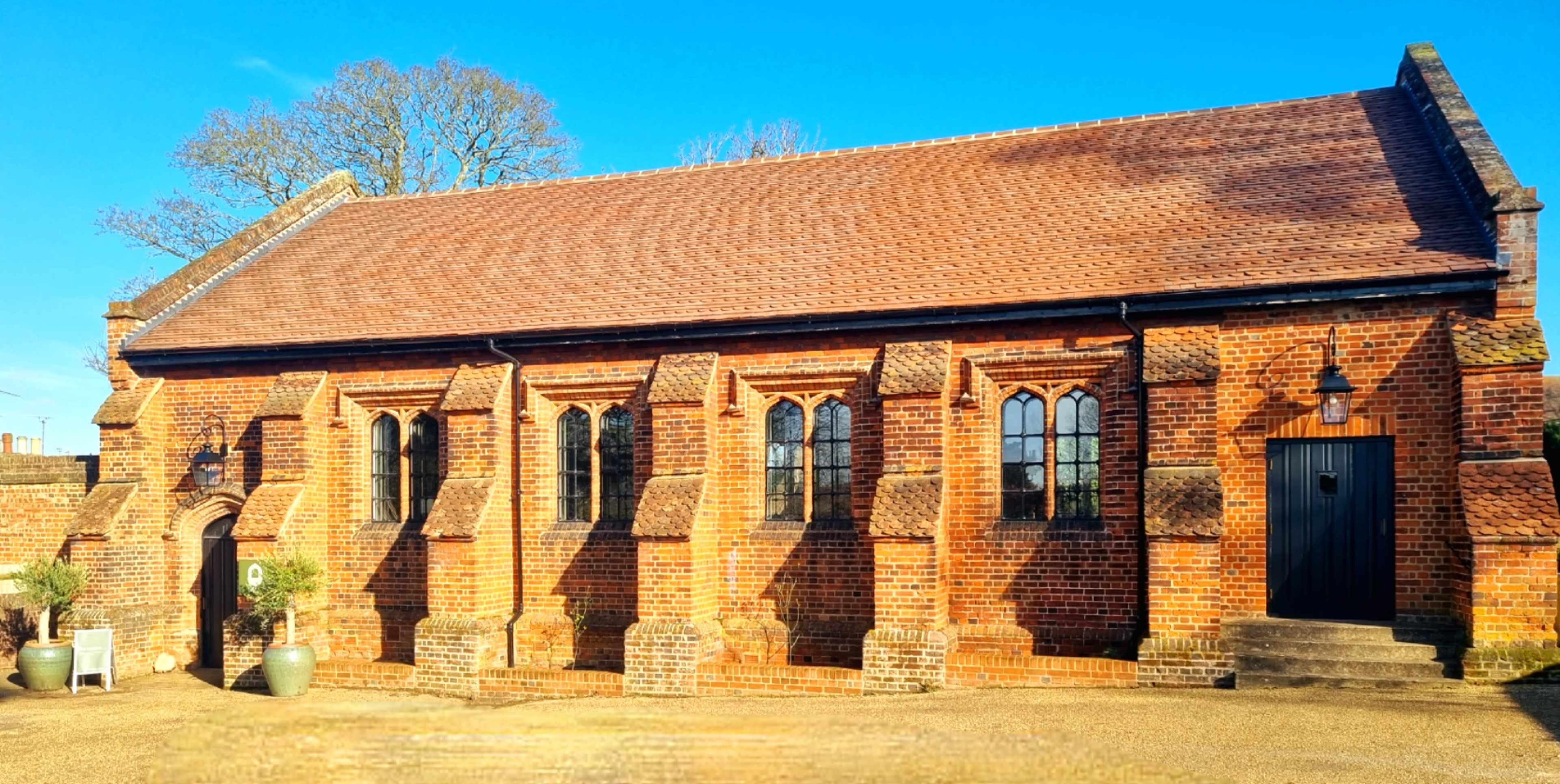 A brick building with multiple arched windows and a door, set against a clear blue sky.