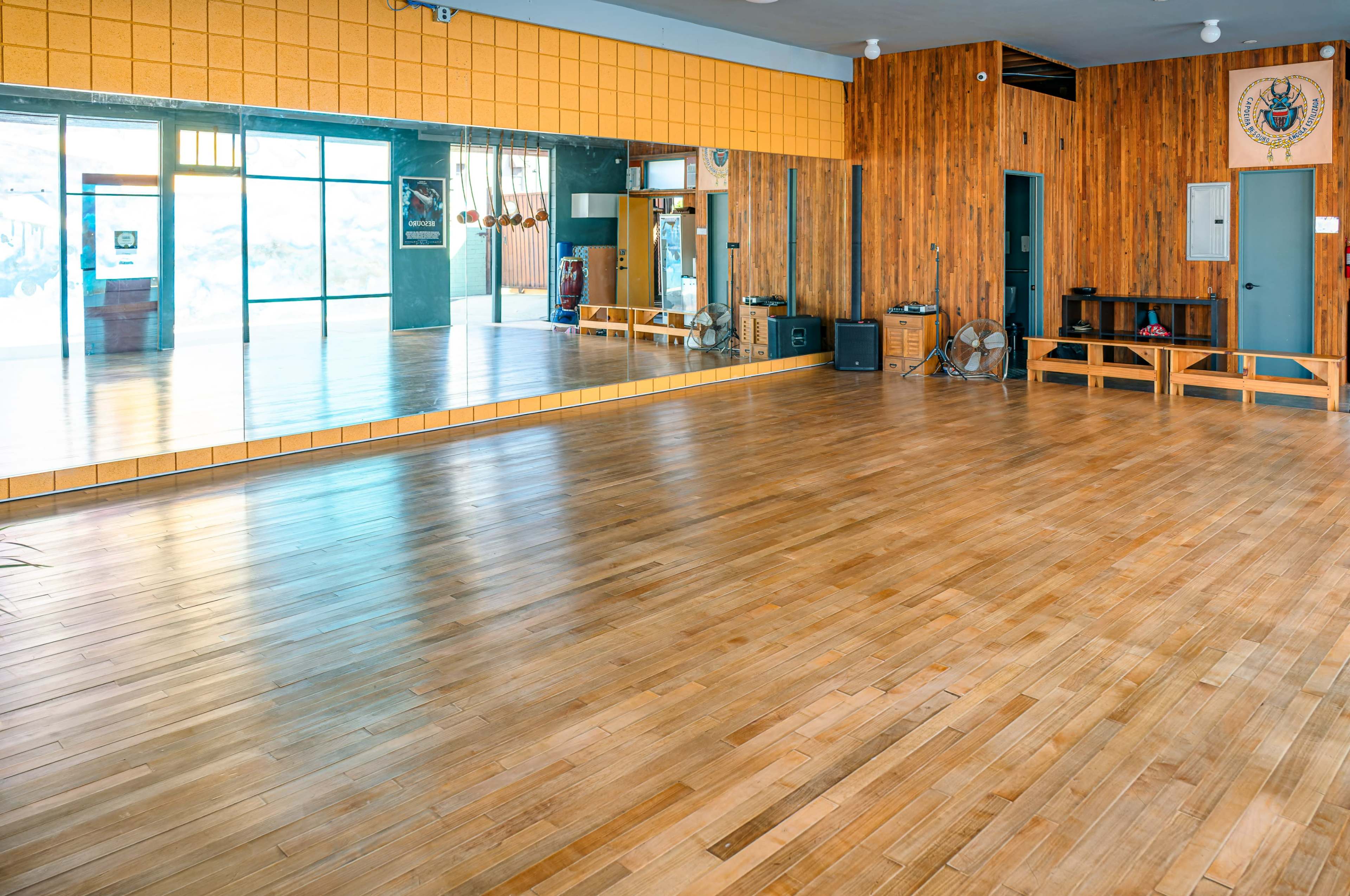 A spacious room with wooden flooring, a large mirror on one wall, and wooden paneling on another.