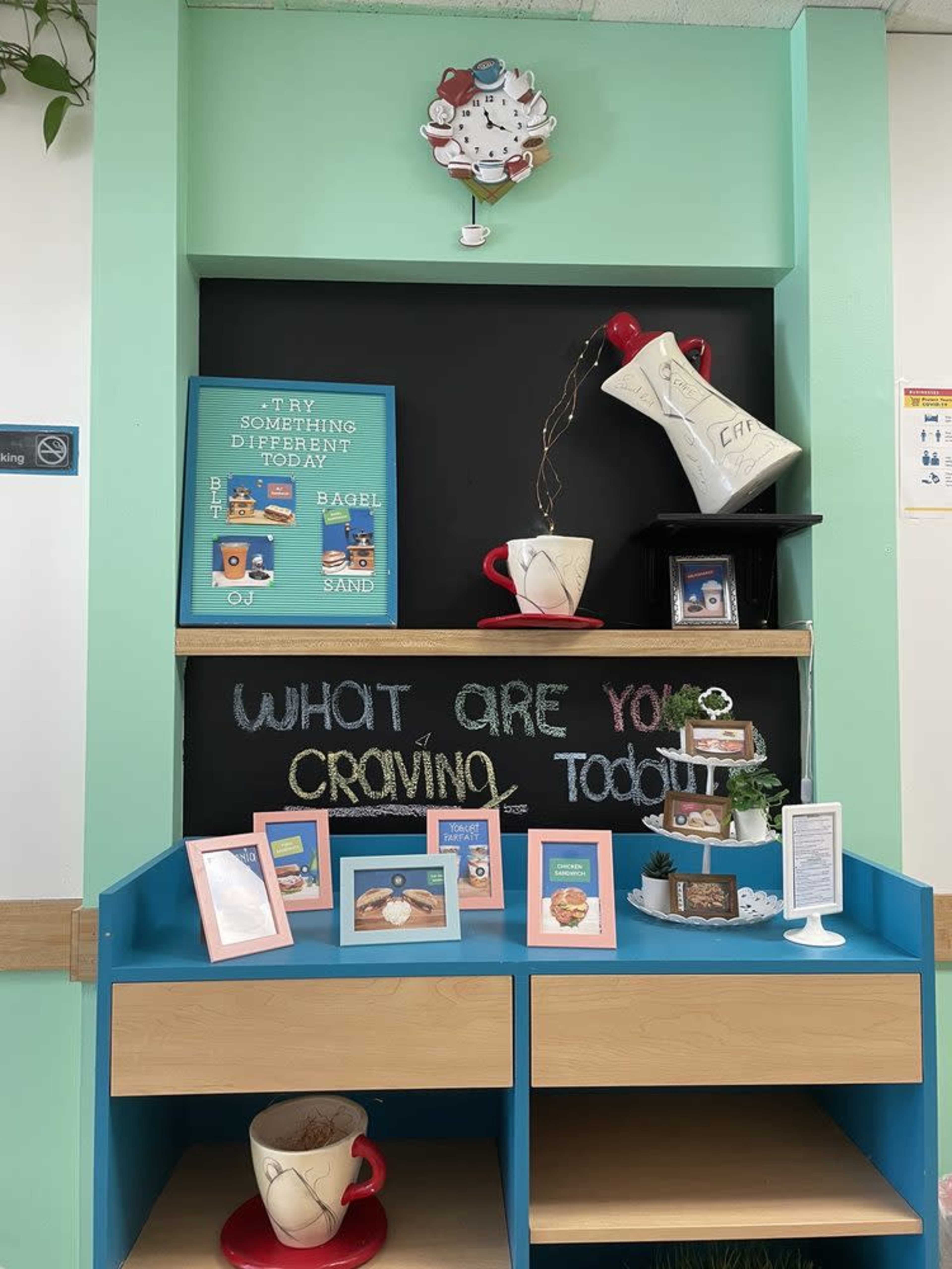 The image shows a colorful display with a chalkboard that reads "WHAT ARE YOU CRAVING TODAY?" and several framed photos of food items on a shelf.