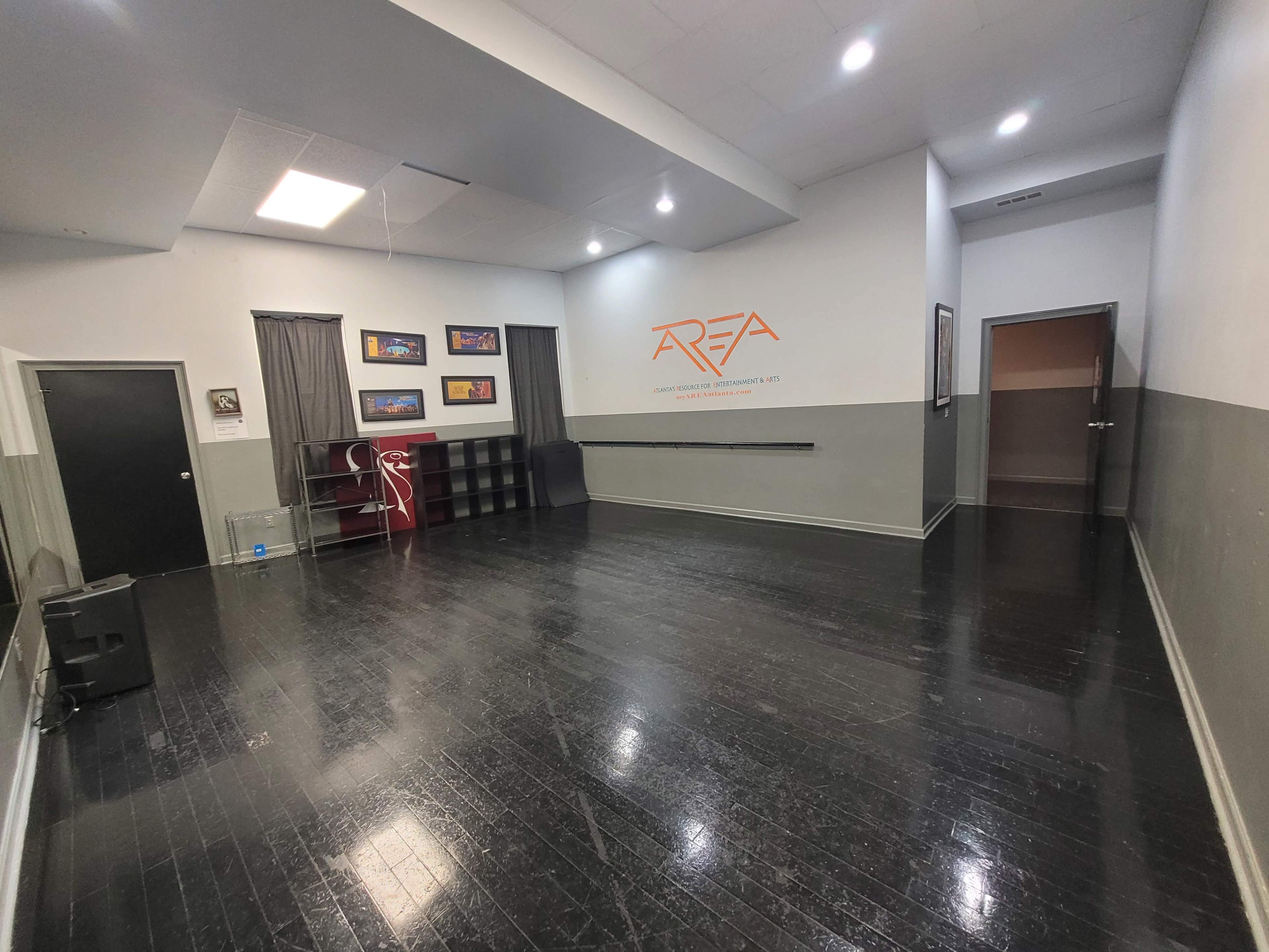 An empty interior space with black flooring, gray walls, and a few framed artworks displayed.