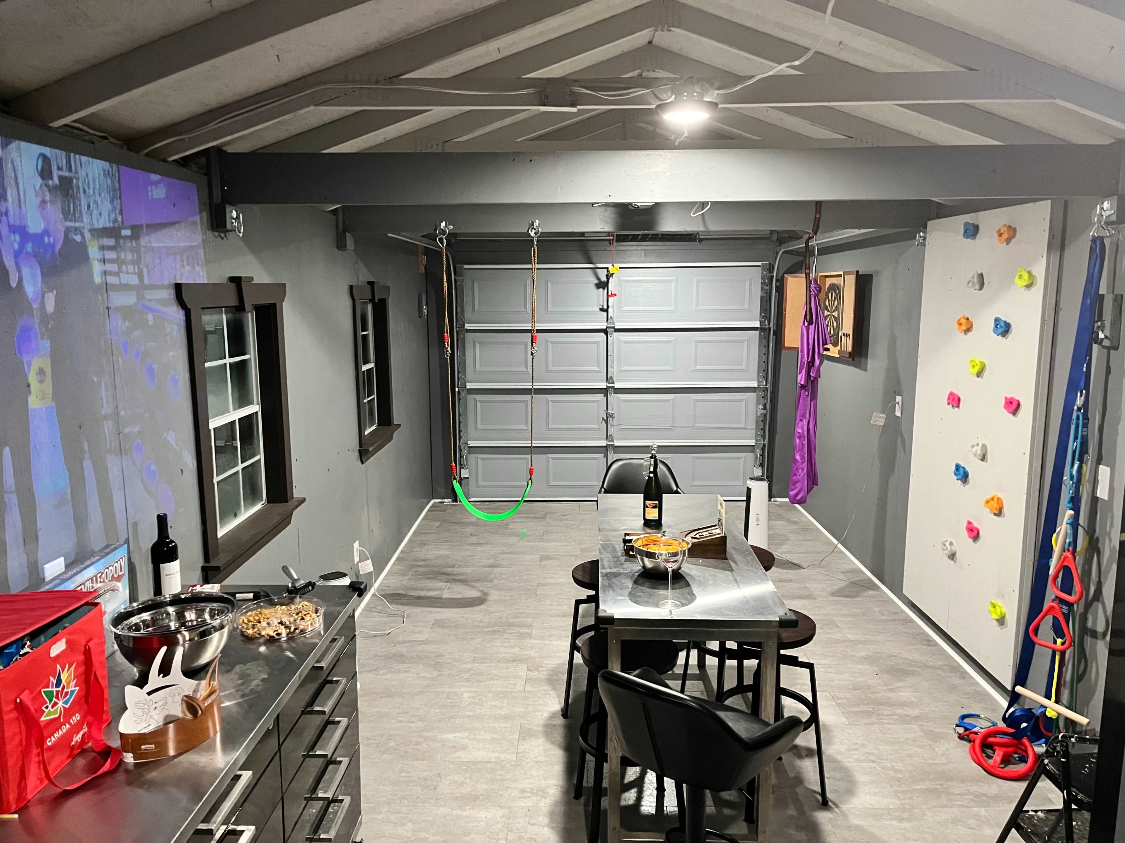 A garage converted into a multifunctional recreational space with a dining table, snack area, and climbing wall.