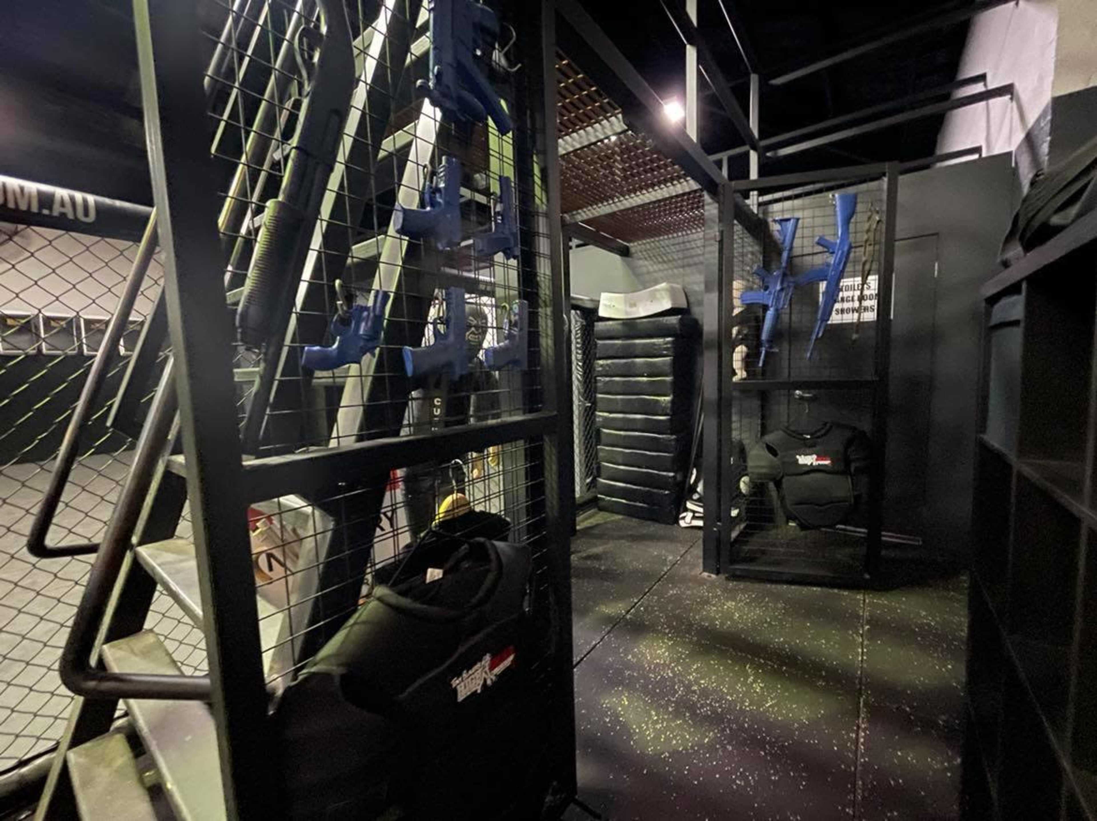 An indoor tactical training space with storage racks for gear and equipment, including protective clothing and equipment for a combat simulation or training exercise.