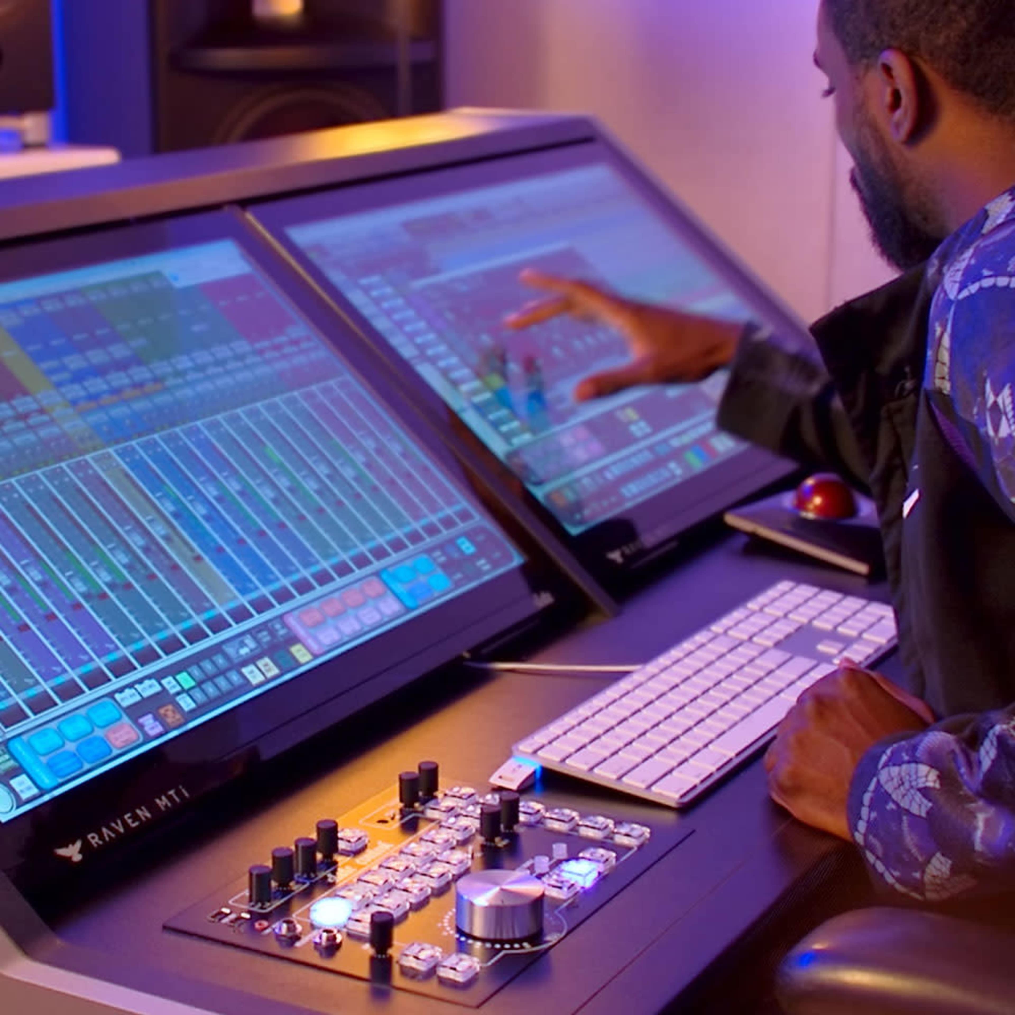 A person operates a digital audio workstation on dual touchscreen monitors in a music studio.