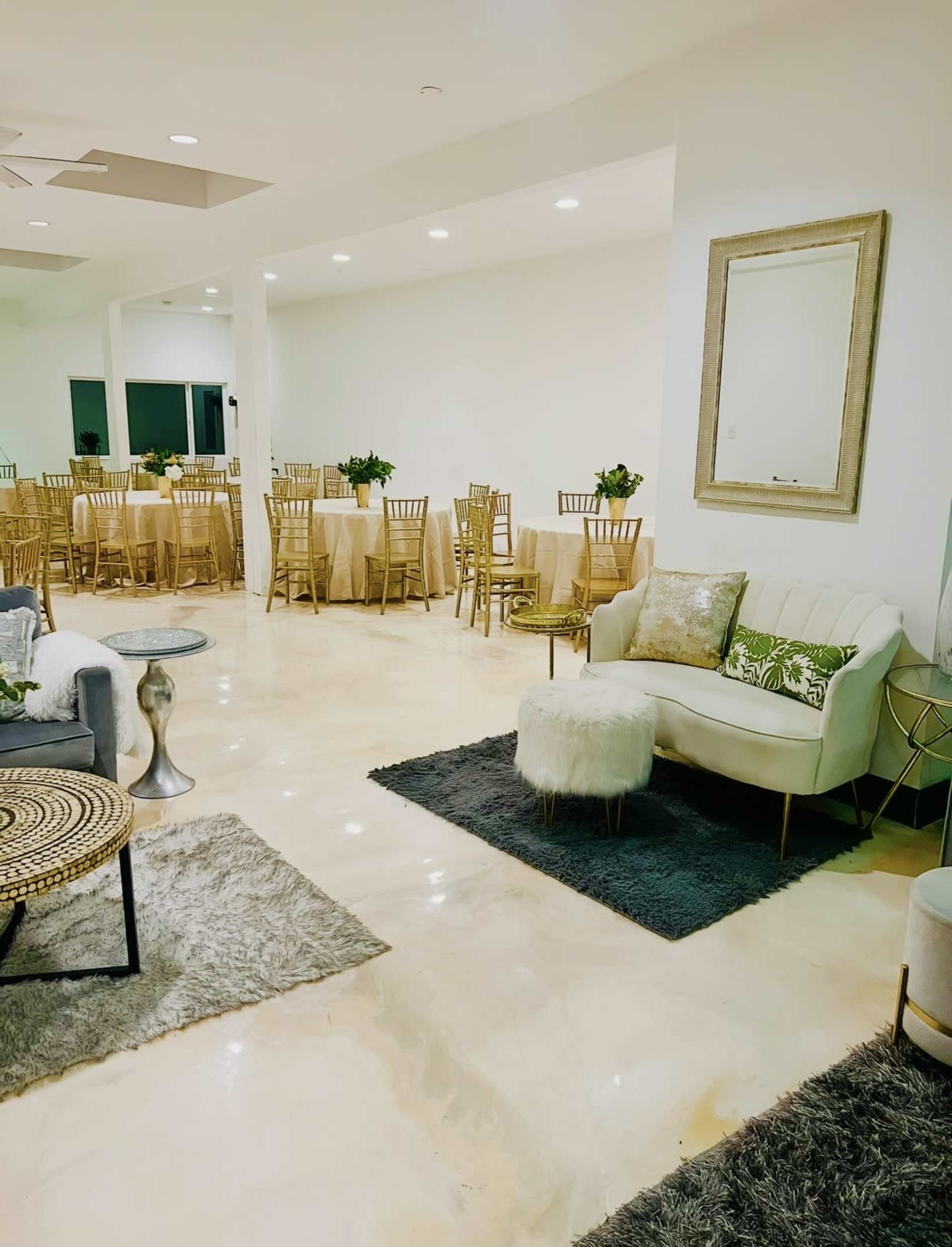 The image shows a spacious indoor event space with elegant seating areas and tables set for dining.