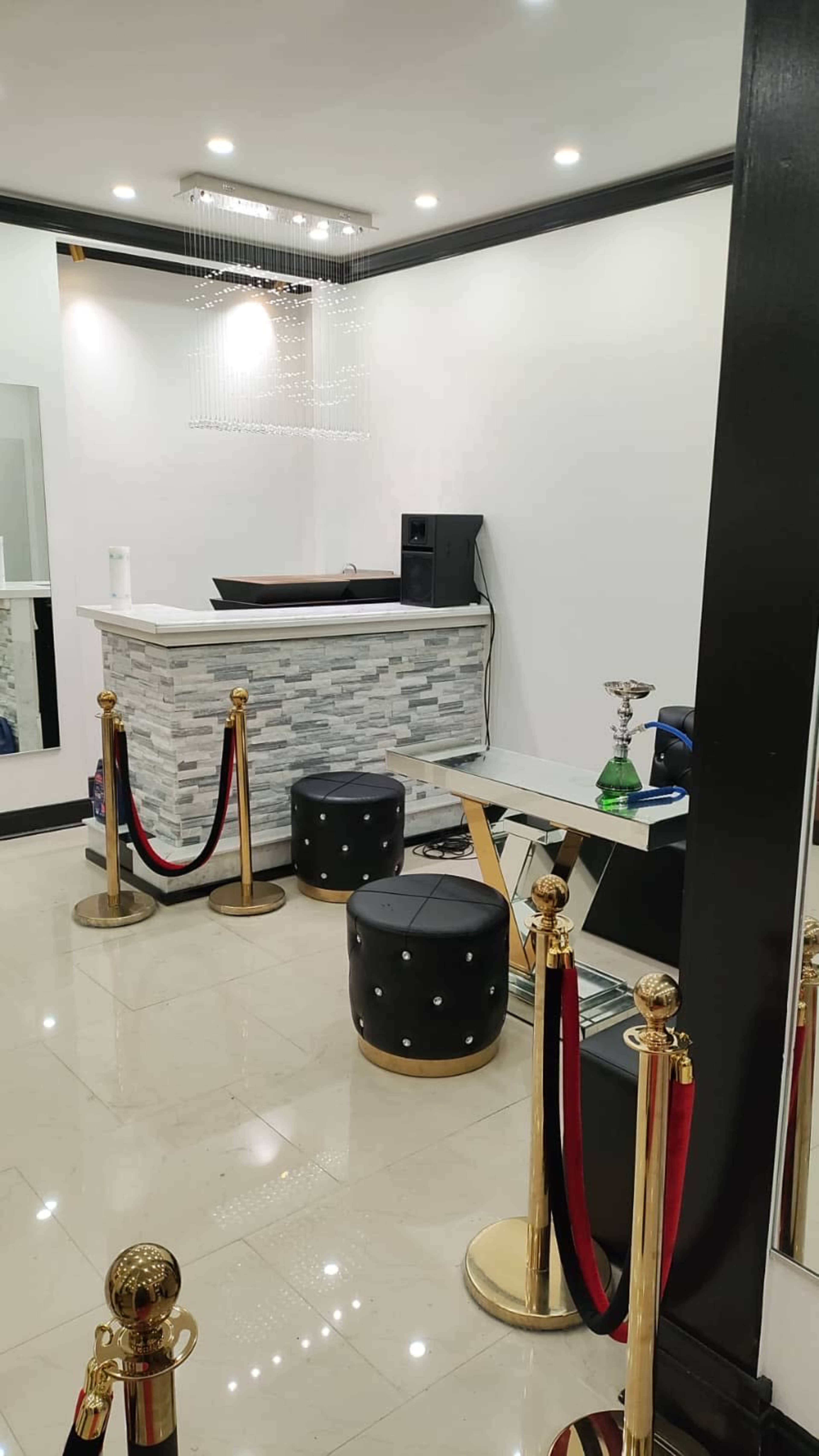 The image shows a modern reception area with a stone-front desk, black seating, and red velvet ropes.