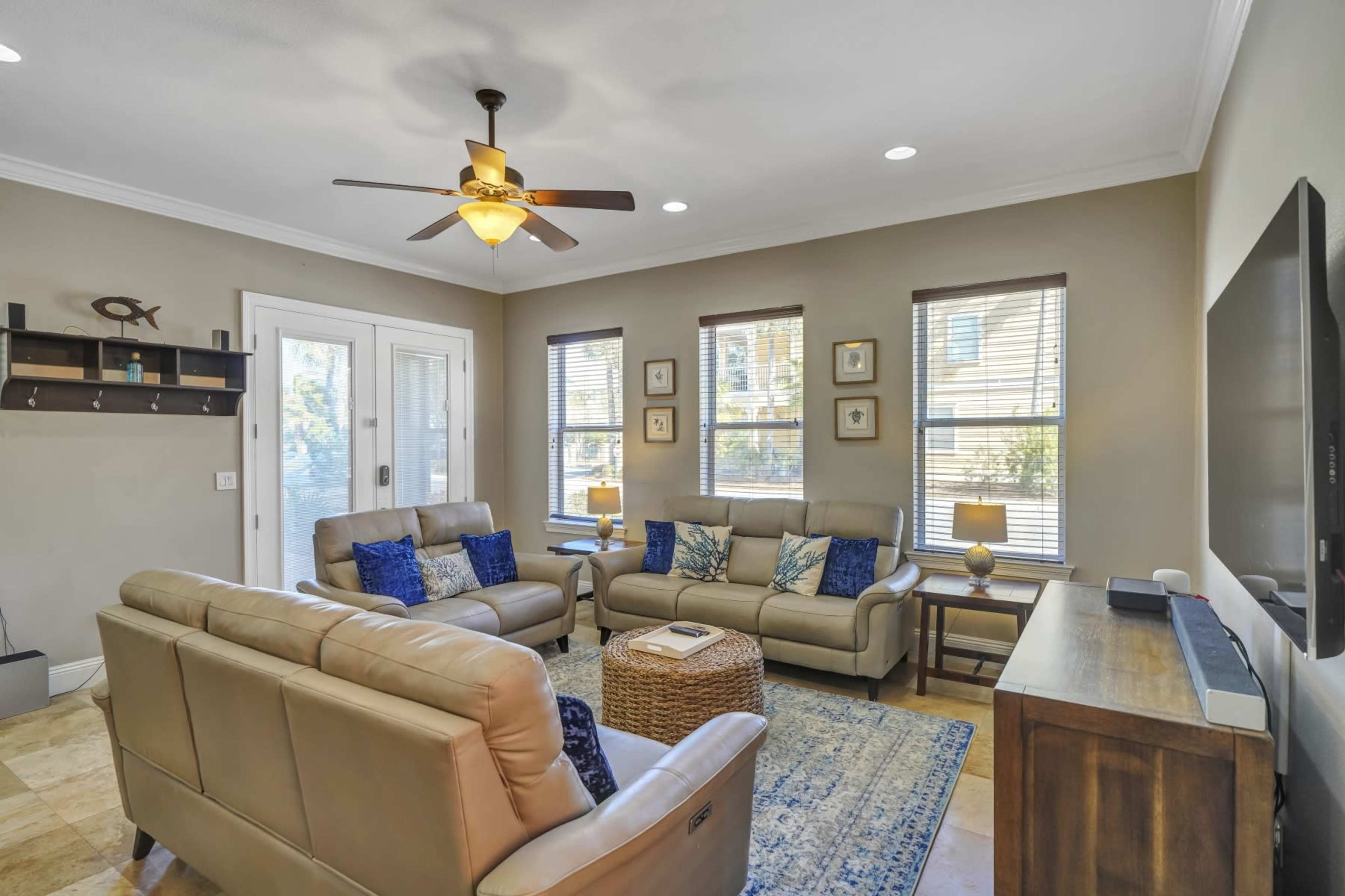 A cozy living room features two sofas, a coffee table, and a TV unit, with natural light coming through the windows.