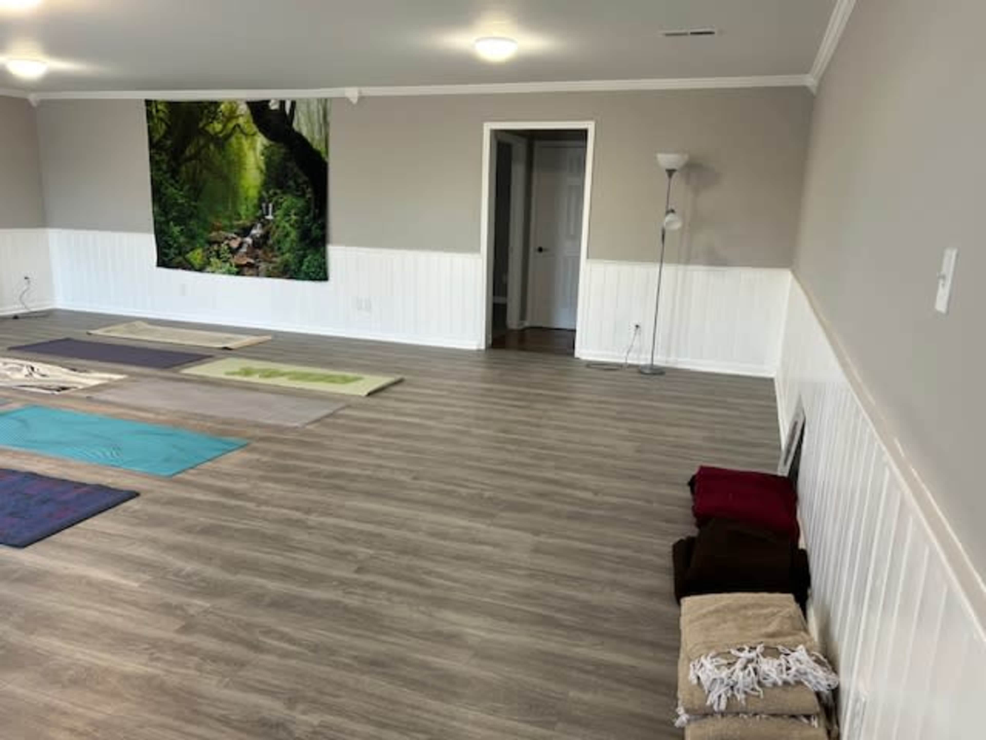 A spacious yoga studio with mats placed on the floor and a large mural of a forest scene on the wall.
