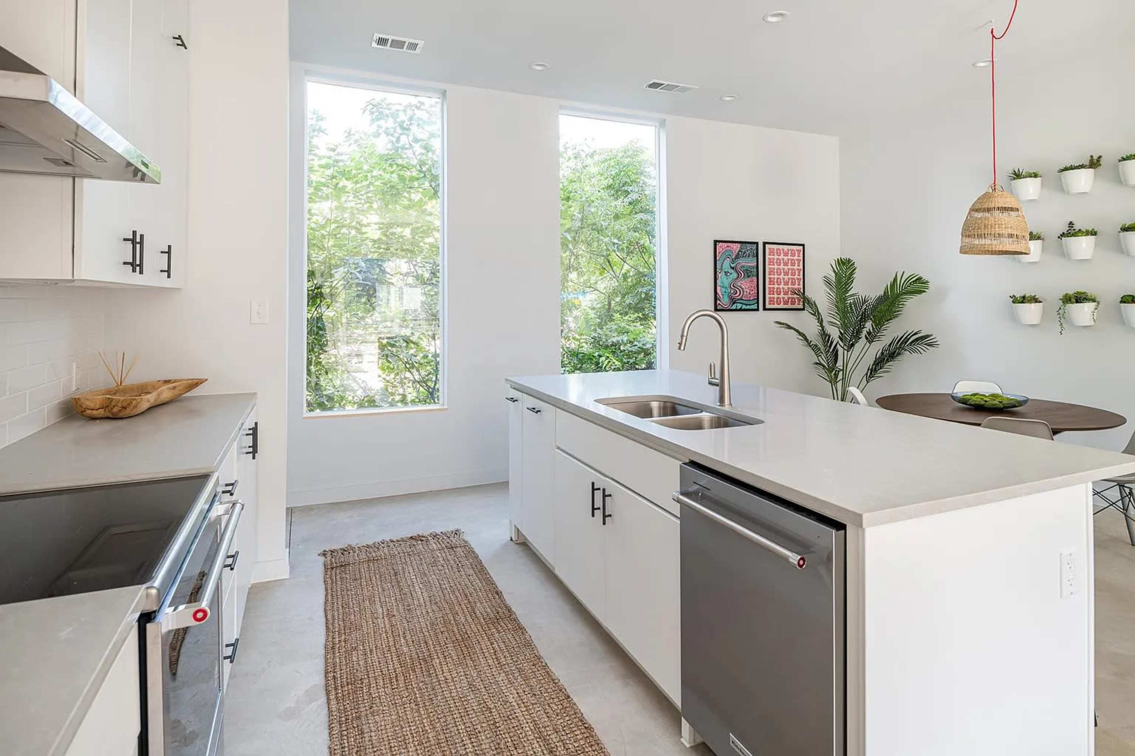 A modern kitchen with a central island, stainless steel appliances, and large windows allowing ample natural light.