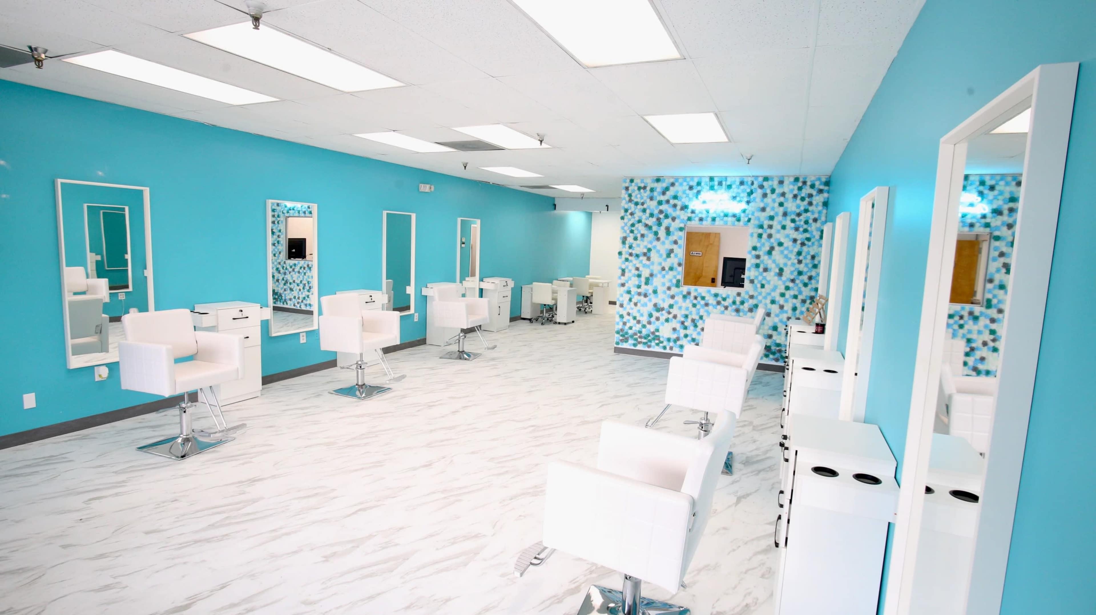 A brightly lit hair salon with turquoise walls, white styling stations, and modern chairs arranged neatly throughout the space.
