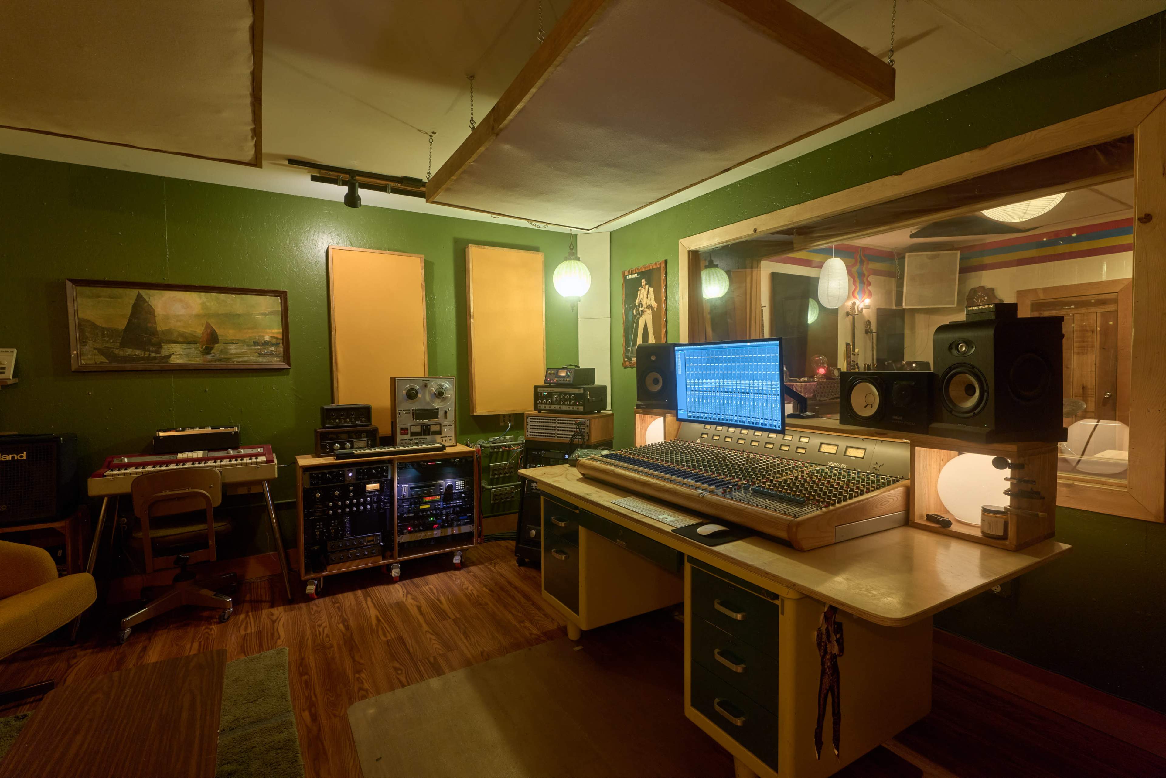 The image shows a vintage recording studio featuring a large mixing console, various music equipment, and acoustic panels on the walls.