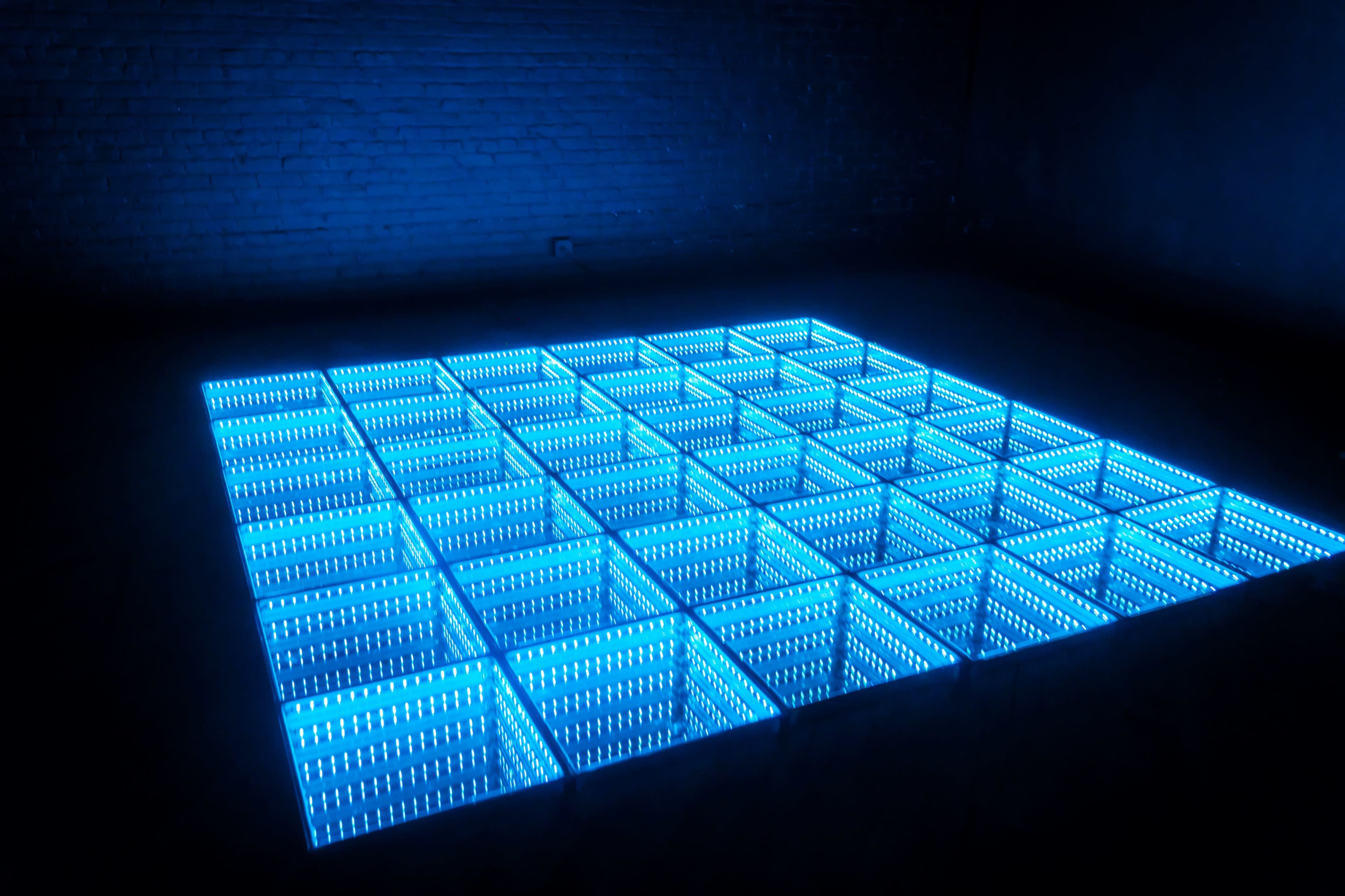 A grid of illuminated blue squares on a dark floor, creating a visually striking pattern.