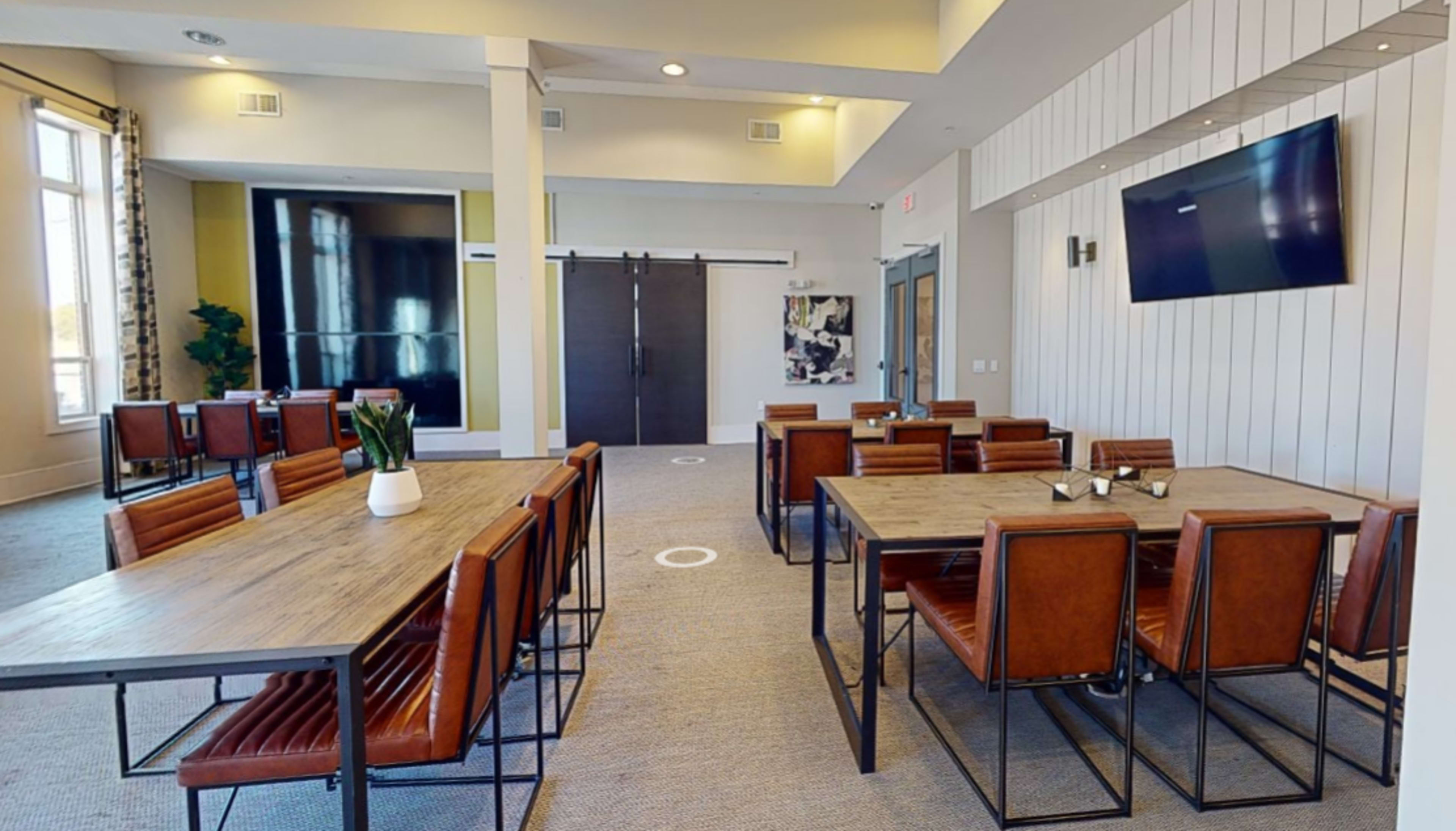 A spacious, modern common area with several tables and chairs arranged for seating.