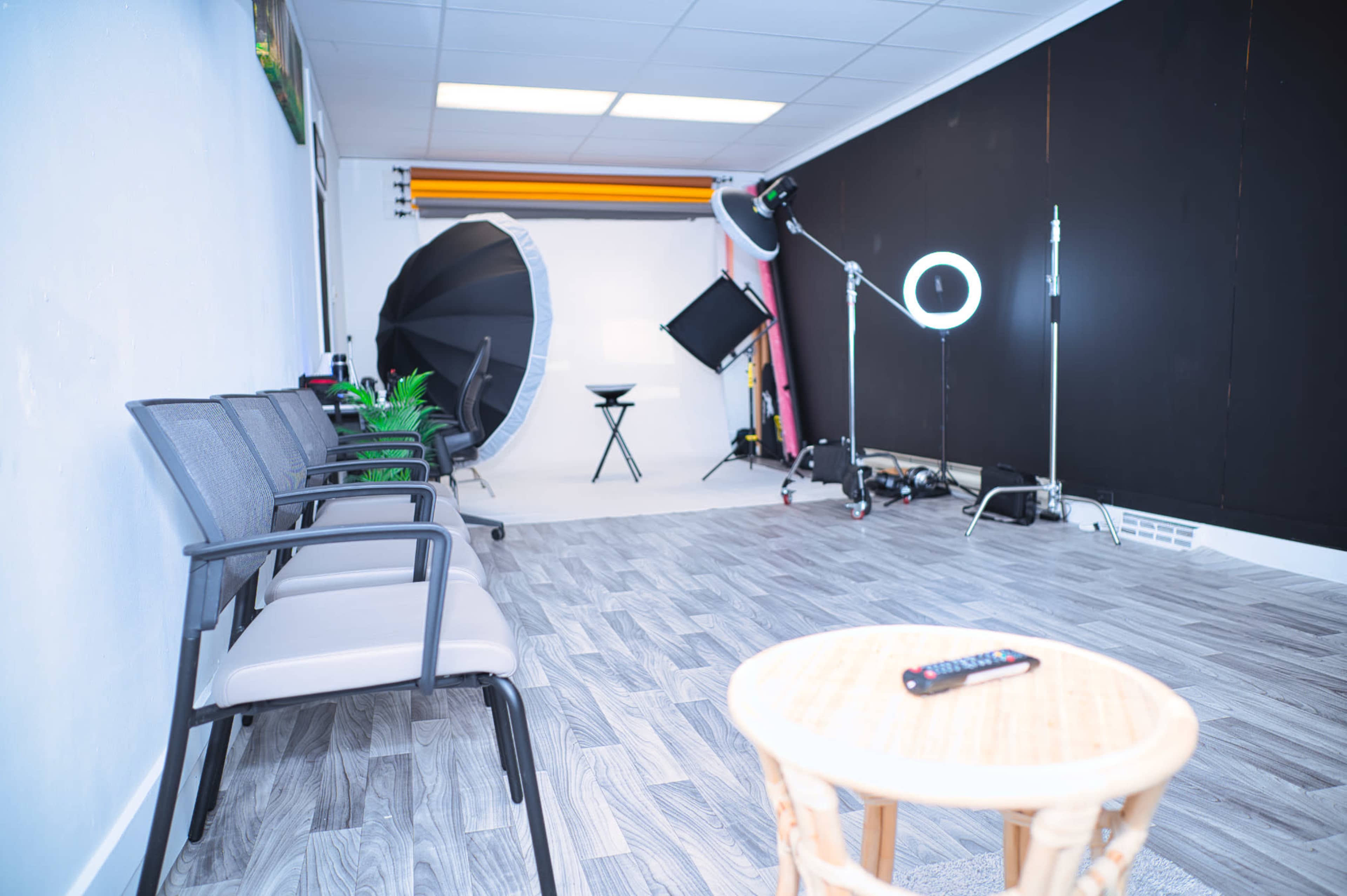 A photography studio featuring chairs, lighting equipment, and a backdrop.
