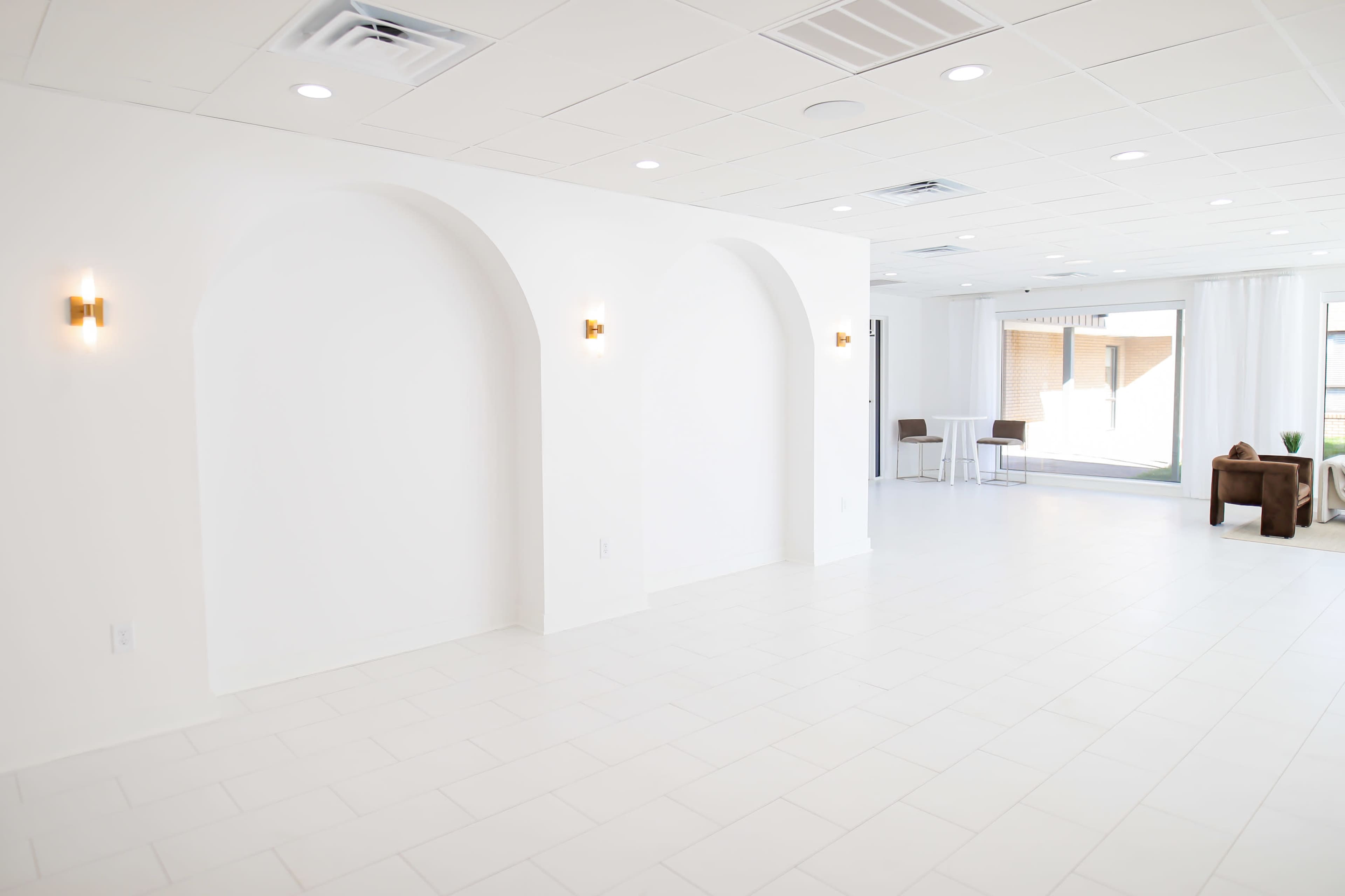 A spacious, bright interior with white walls, arched niches, and minimalist furniture.