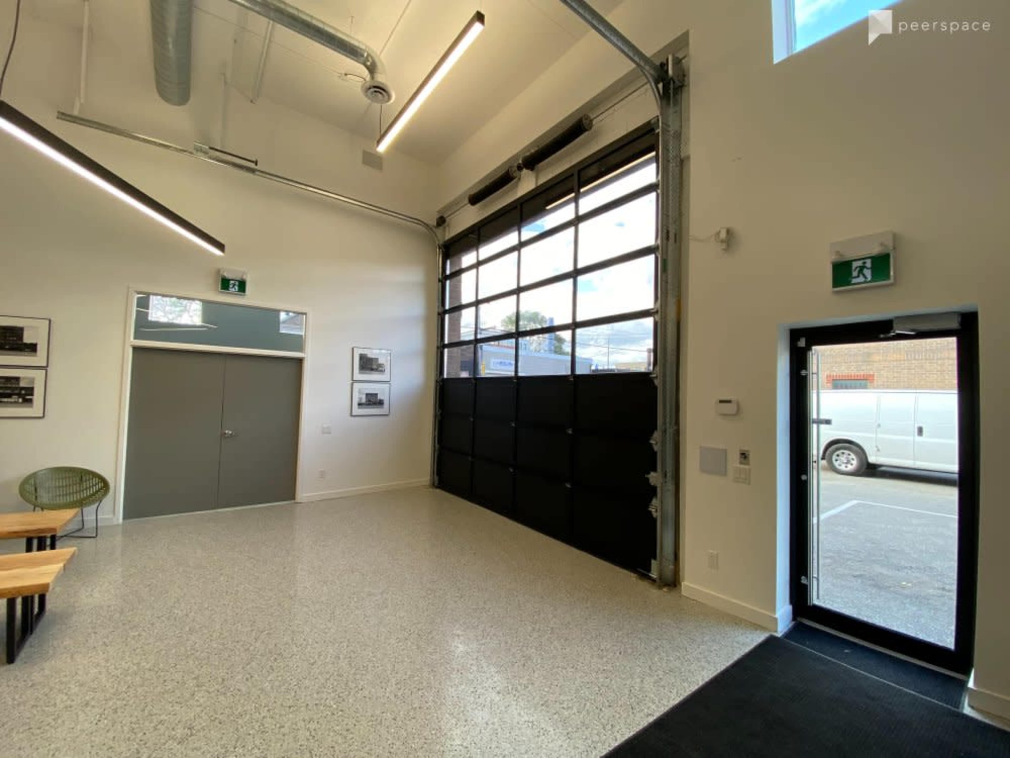 A modern interior space with a large glass garage door, a simple entryway, and minimal furnishings.
