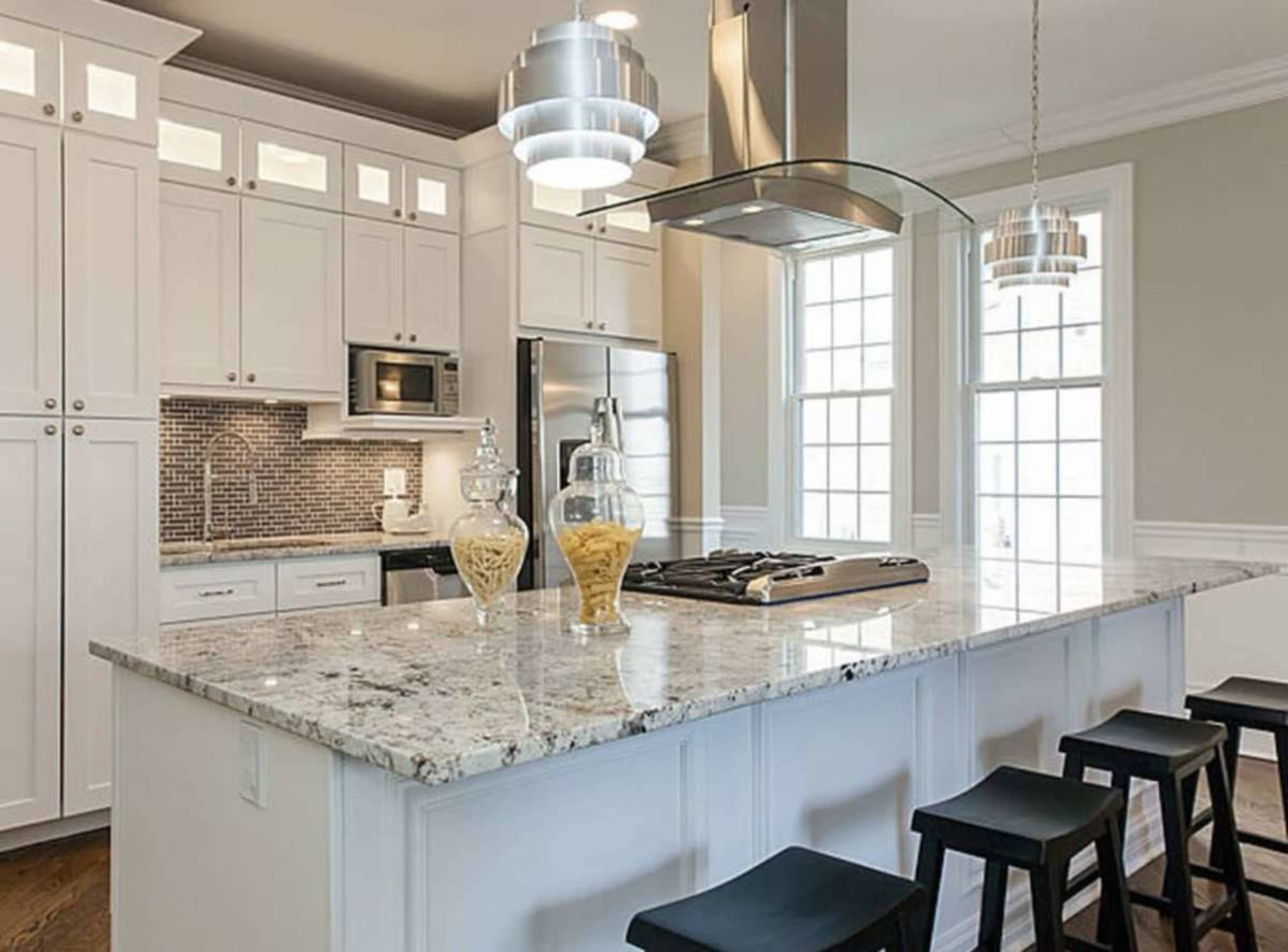 The kitchen features white cabinetry, a central island with a granite countertop, and modern stainless steel appliances.