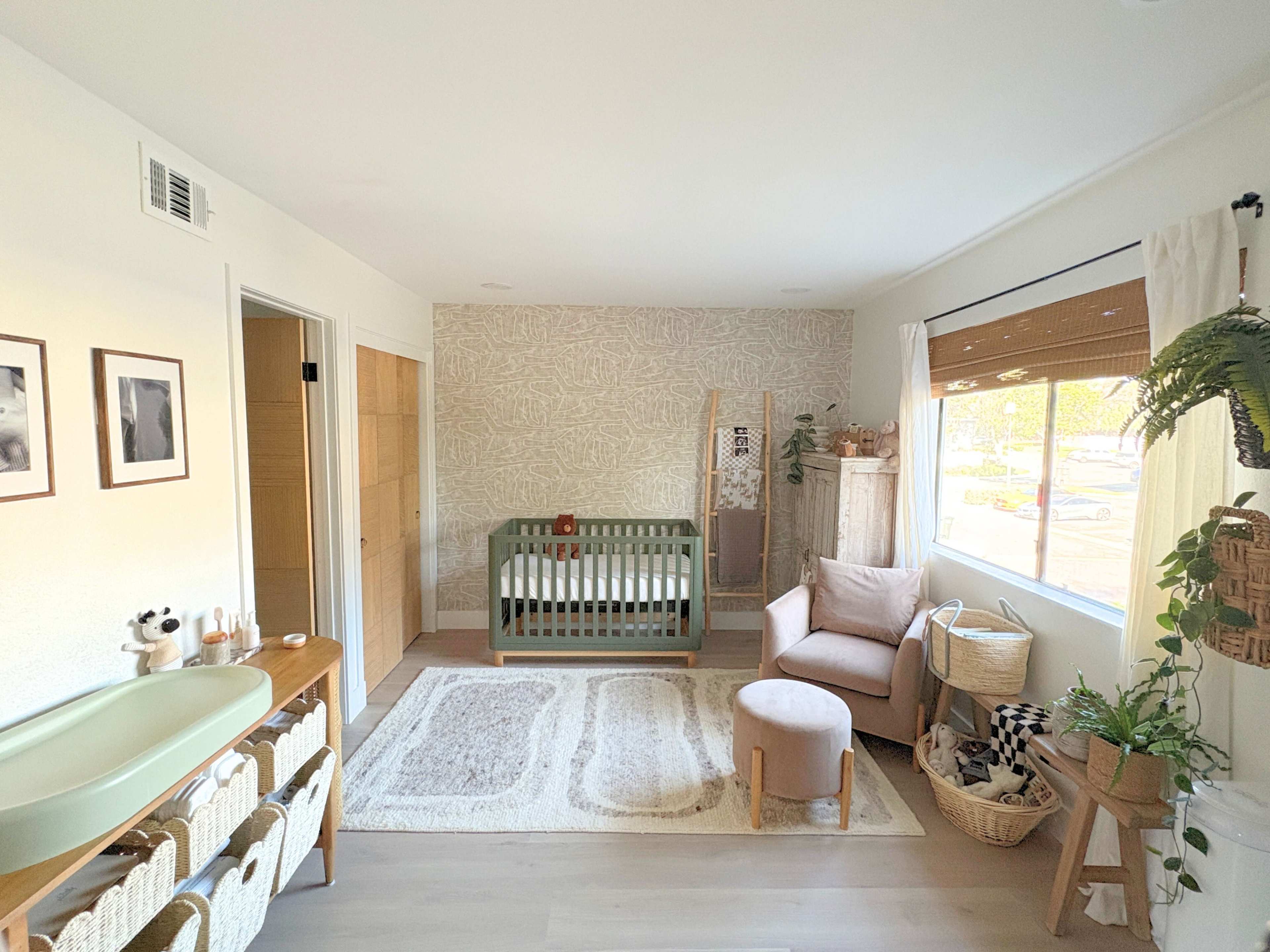 The image depicts a modern nursery featuring a crib, soft seating, and a variety of decorative elements against a light-colored wall.