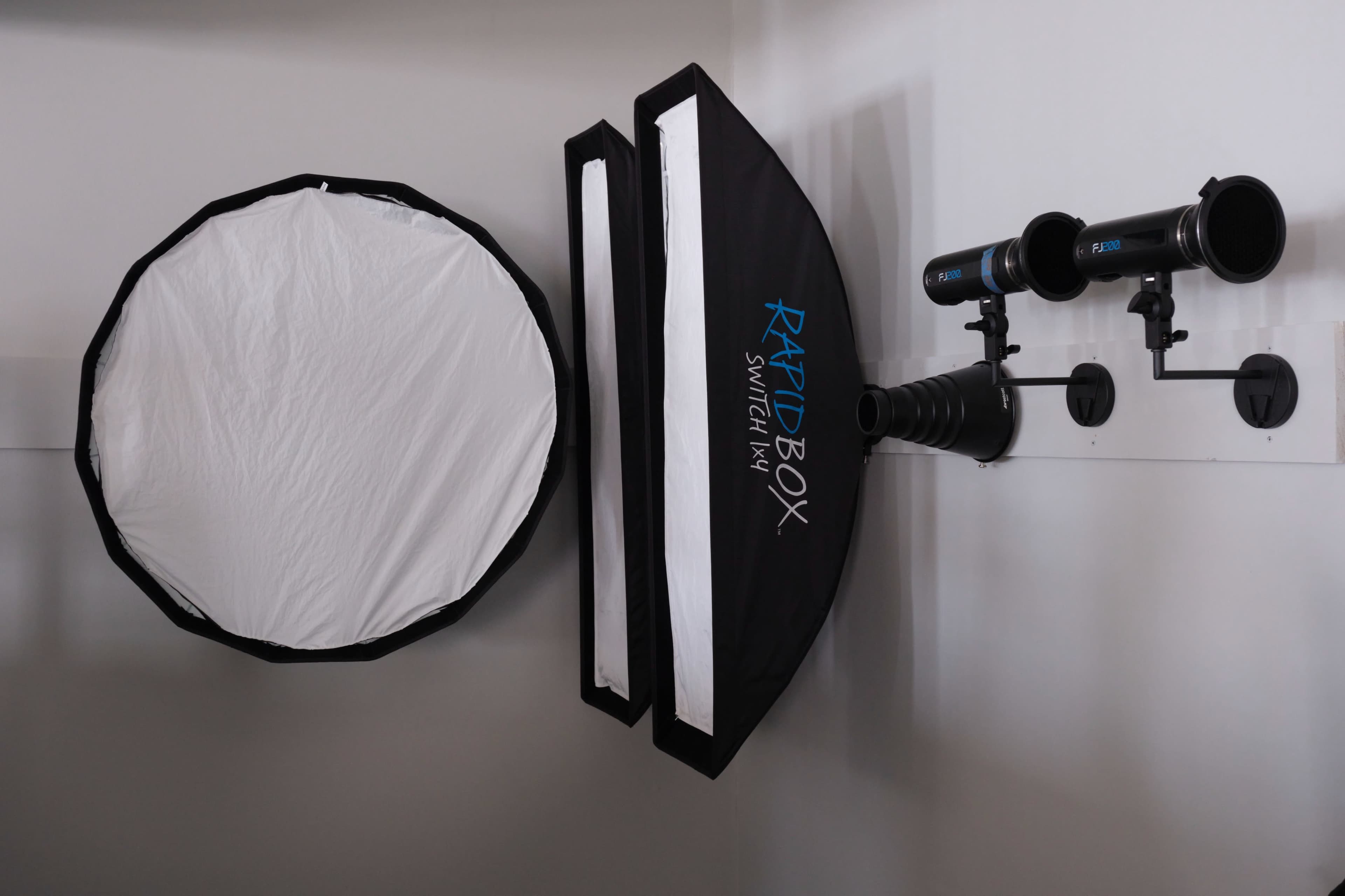 The image shows a wall-mounted lighting setup with two softboxes and a circular reflector.