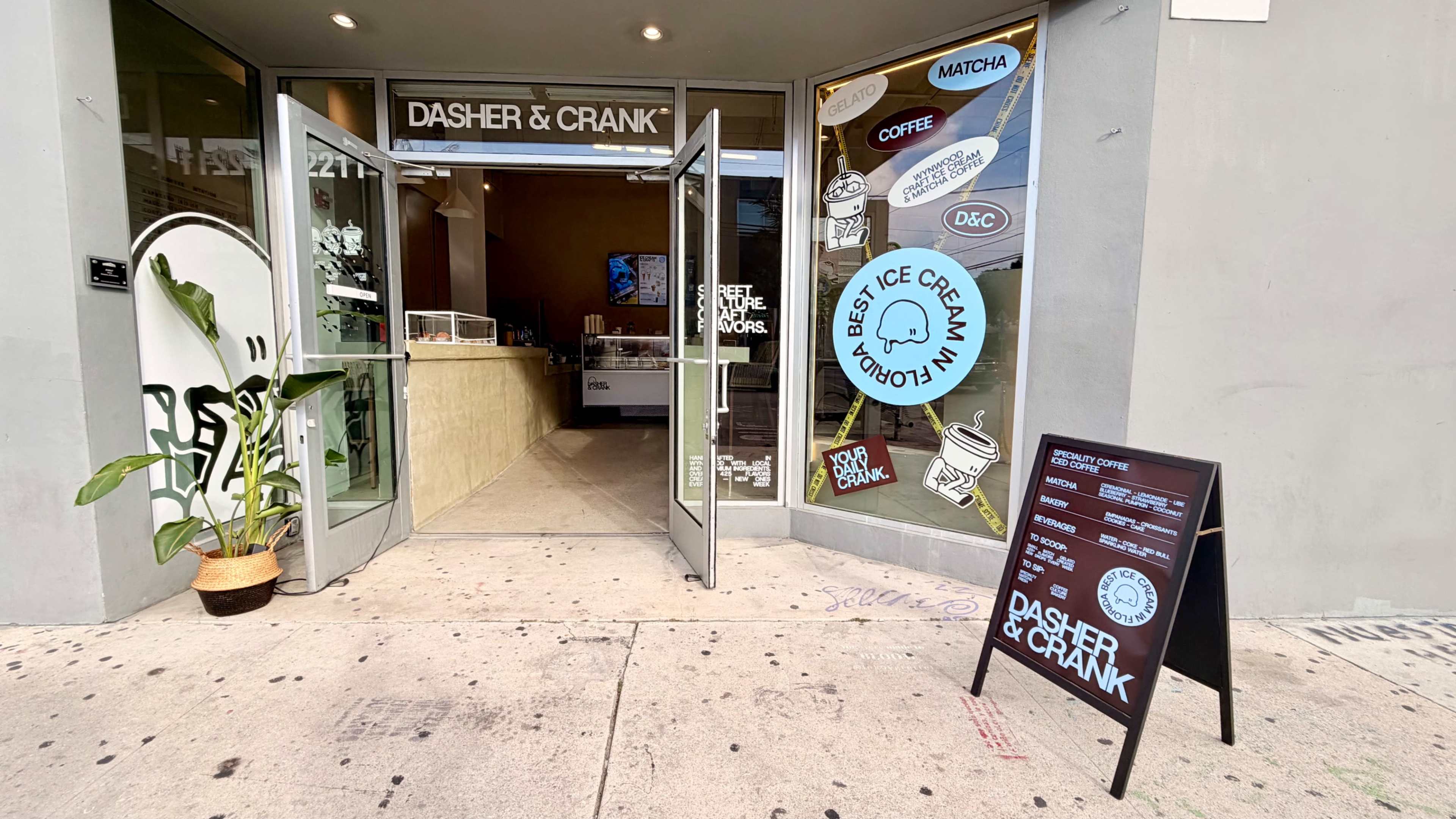 The image shows the entrance of an ice cream shop named "Dasher & Crank," featuring colorful signage and a sandwich board displaying menu items.