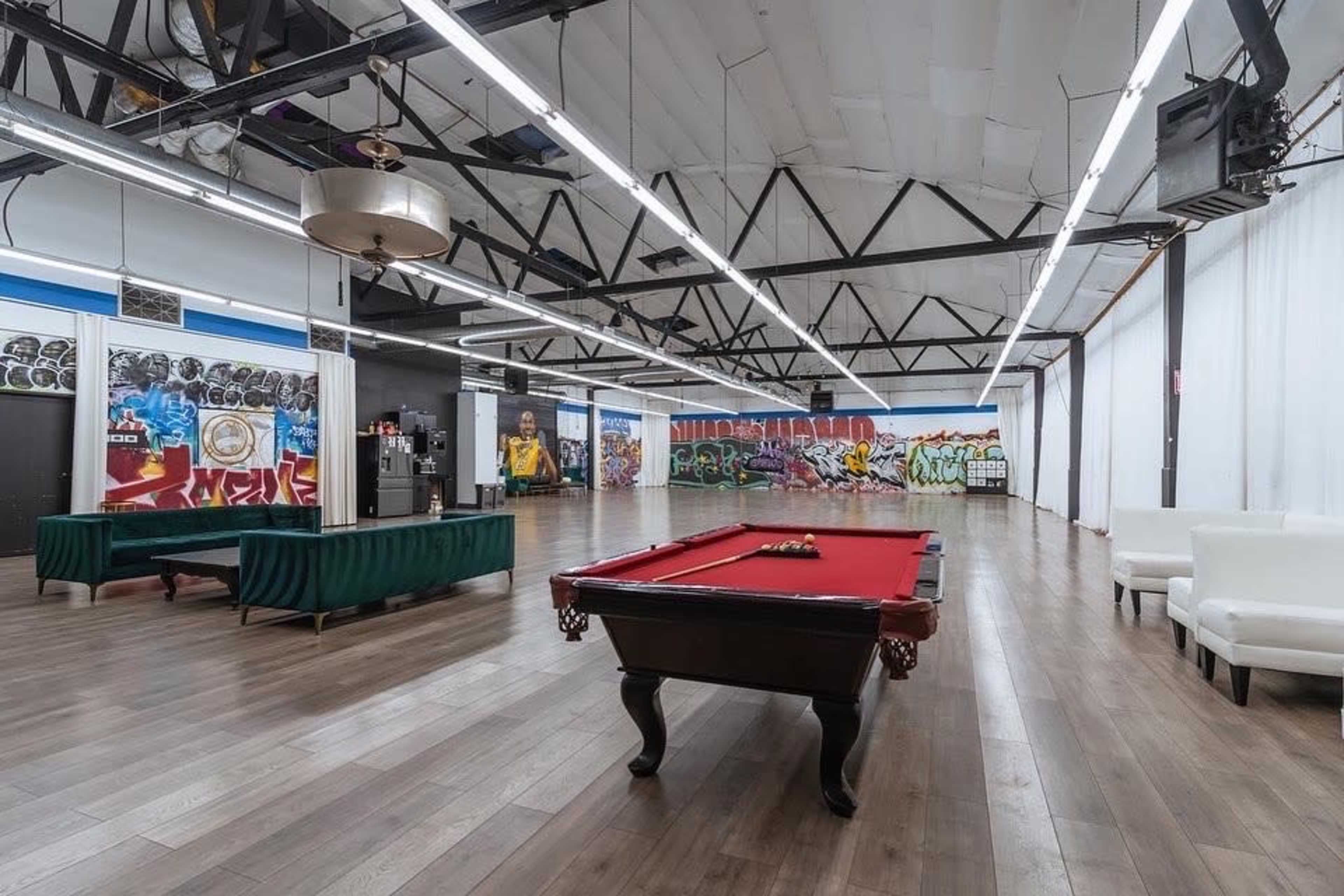 The image shows an open space with a red pool table, green billiard table, and walls adorned with colorful graffiti.