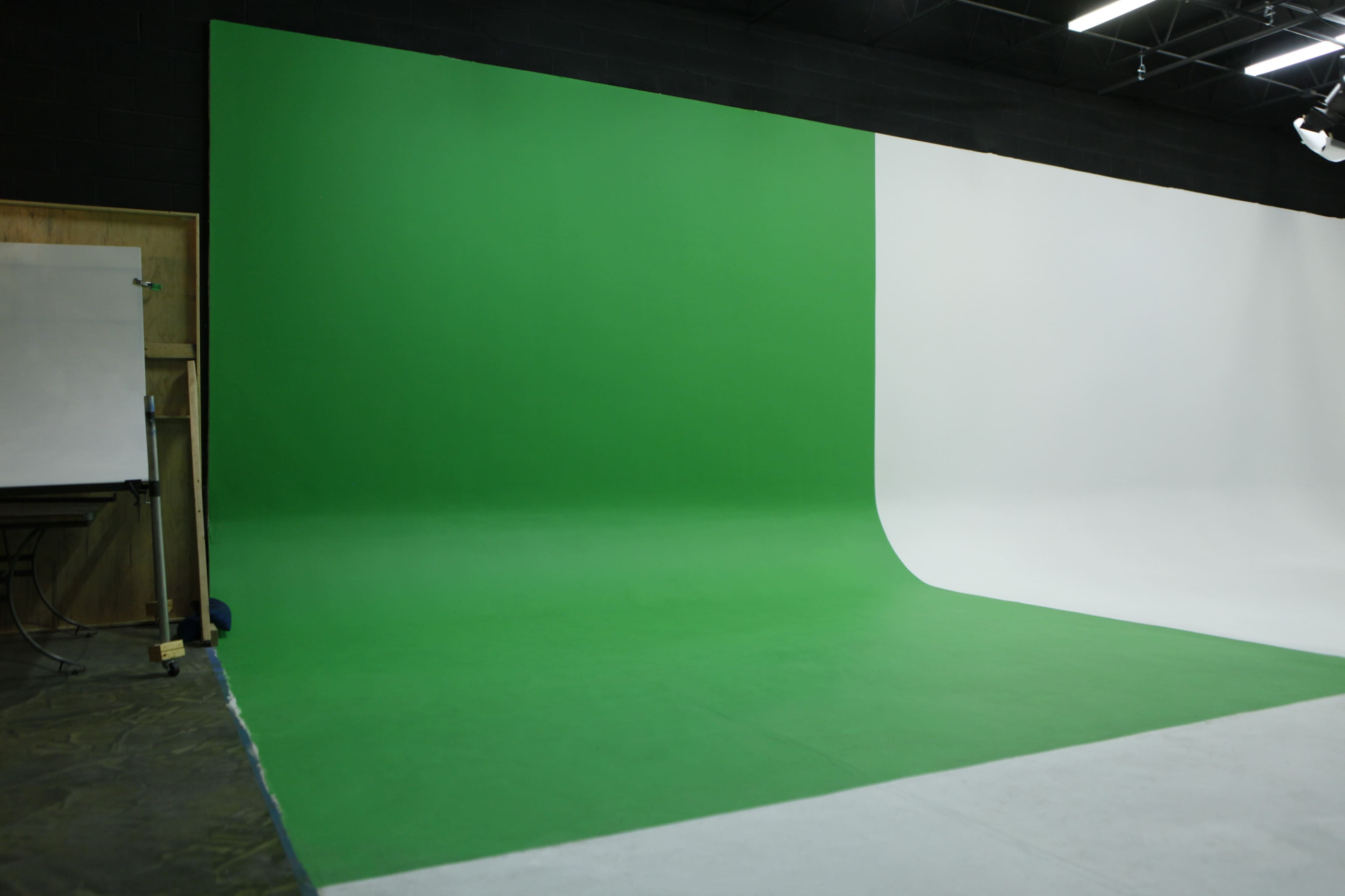A studio features a green screen on one side and a white backdrop on the other.