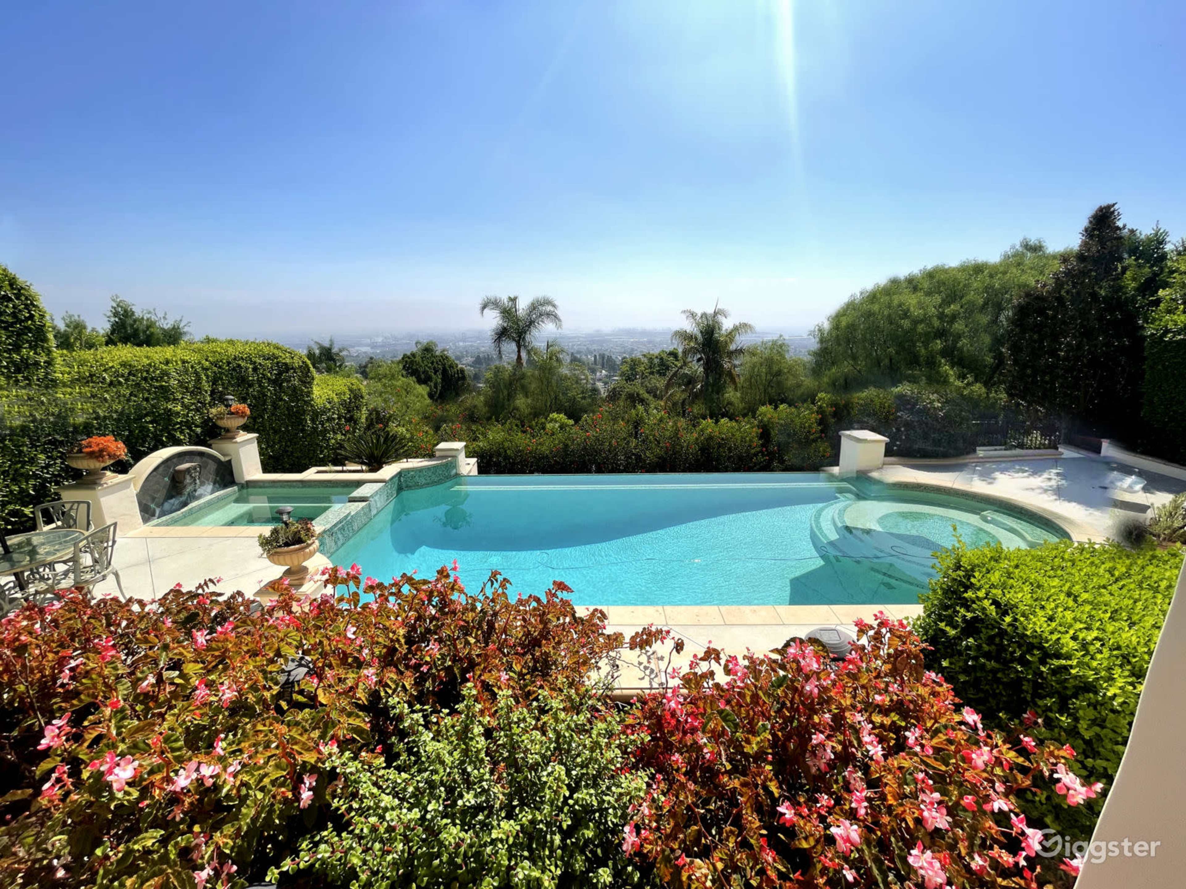 A clear swimming pool surrounded by landscaped gardens and a view of distant hills.
