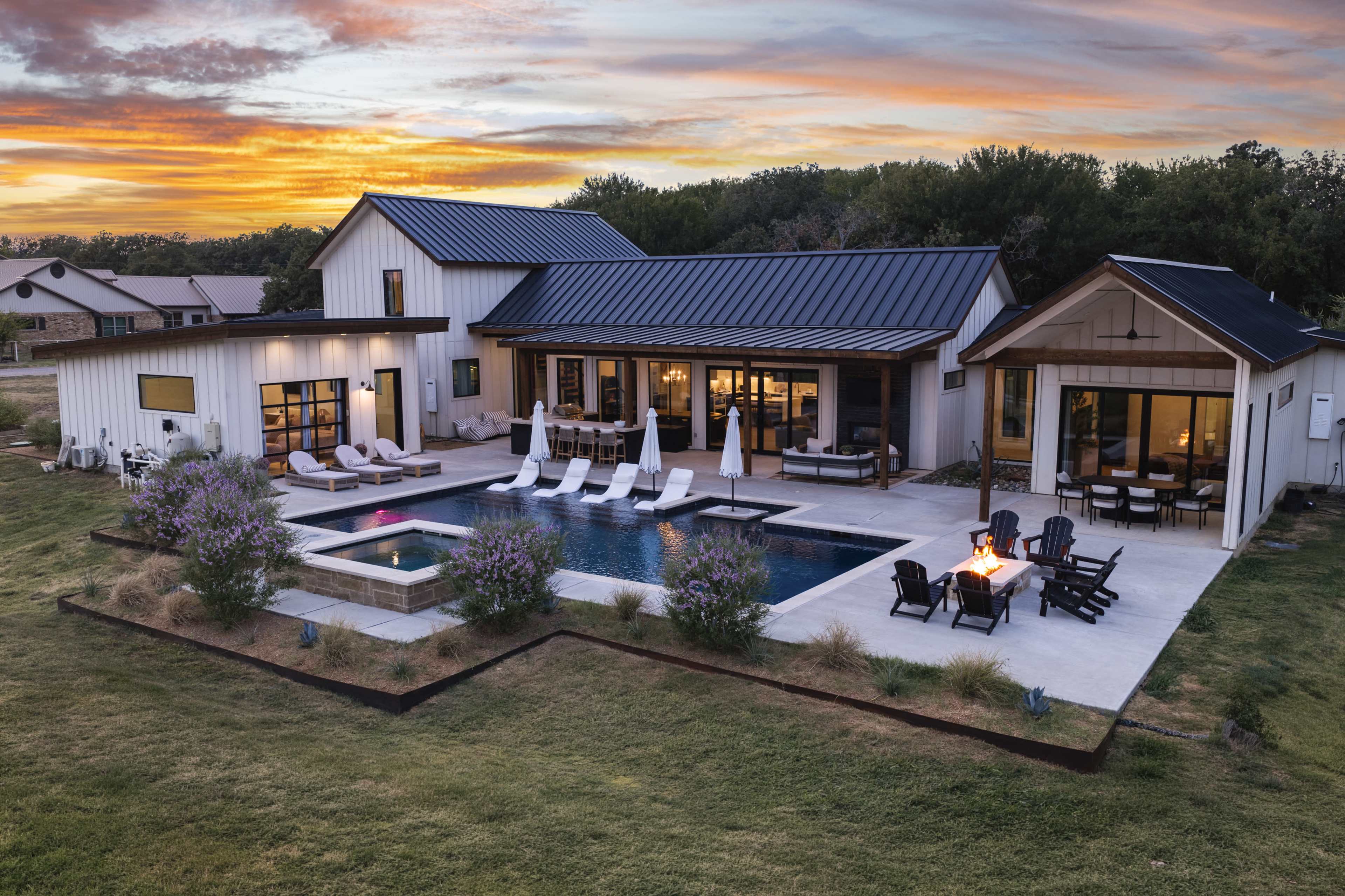 The image shows a modern house with a swimming pool, surrounded by lush greenery and a sunset sky in the background.