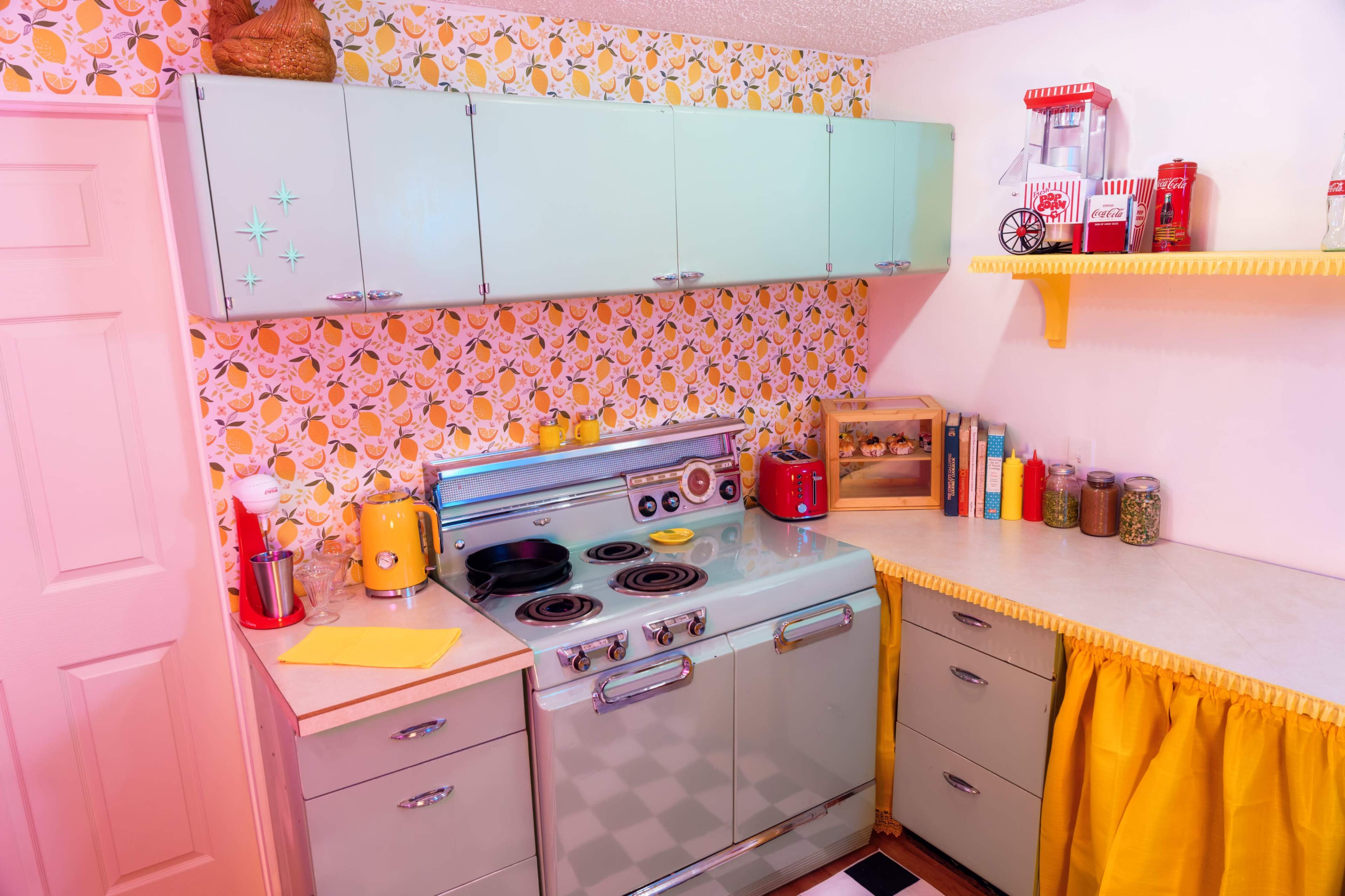 The image features a retro-style kitchen with mint green cabinets, a vintage stove, and yellow floral wallpaper.