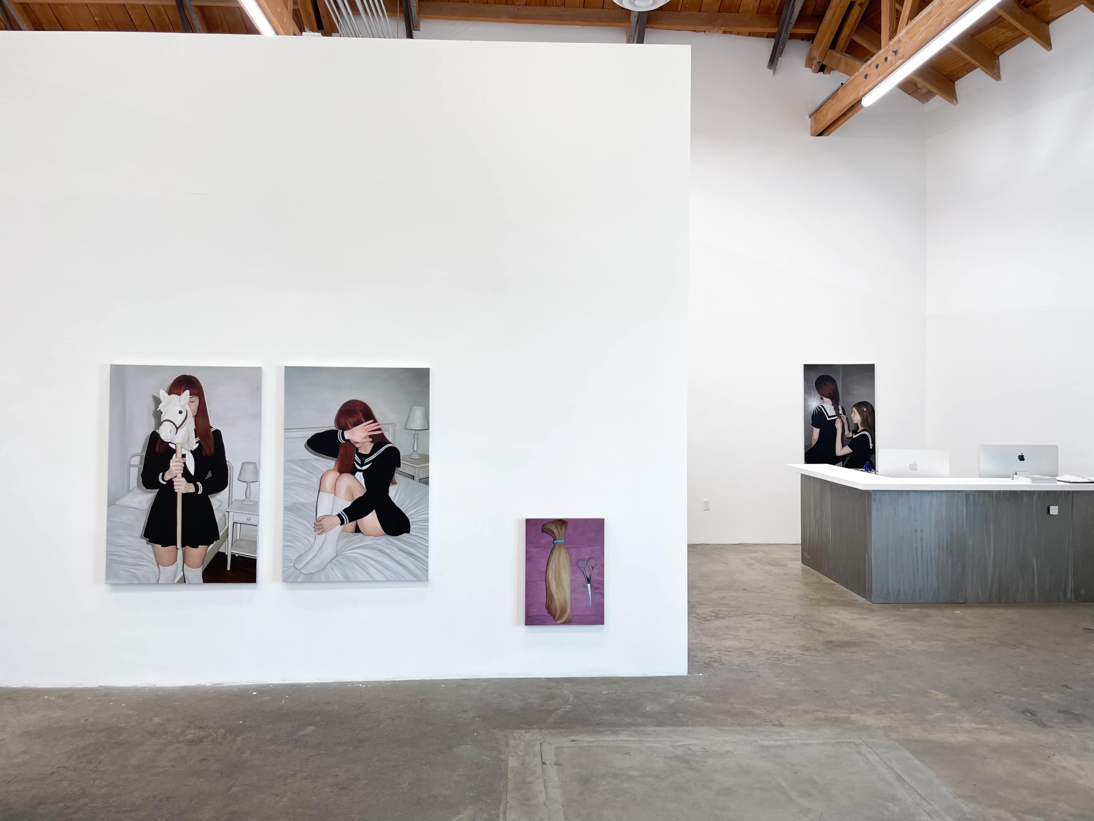 The image shows an art gallery interior with two large framed paintings of a woman, one holding a stuffed animal, and a smaller artwork on the wall, alongside a reception desk.