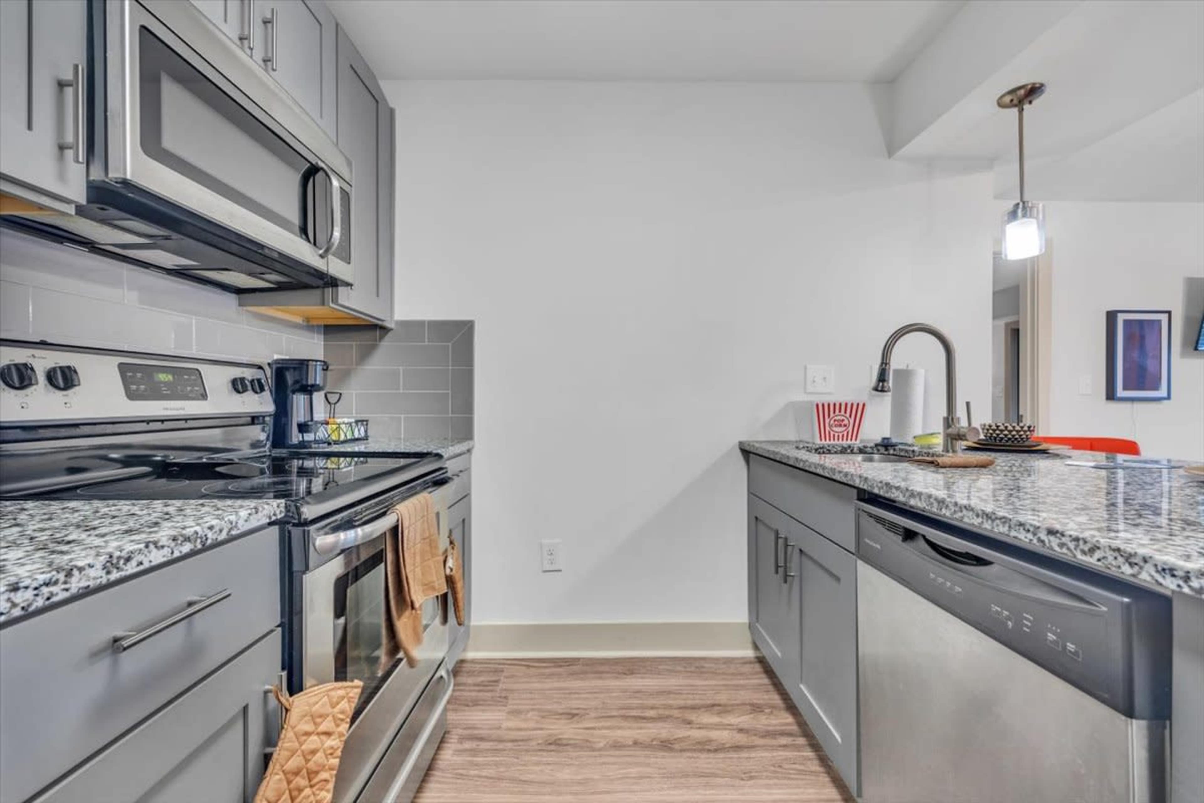 A modern kitchen features stainless steel appliances, granite countertops, and gray cabinetry.