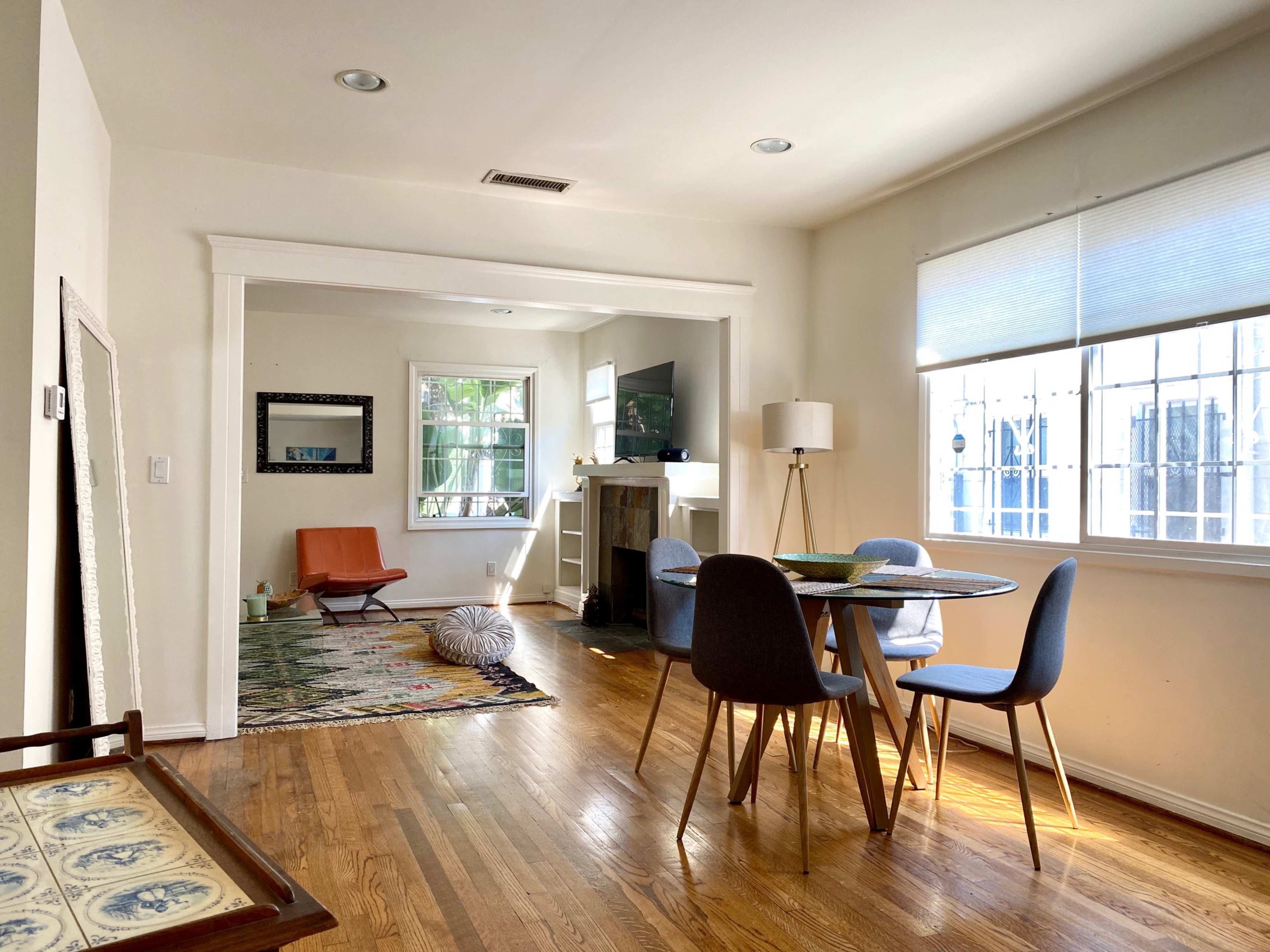 A bright room features a dining table with chairs, a cozy seating area, and hardwood flooring.