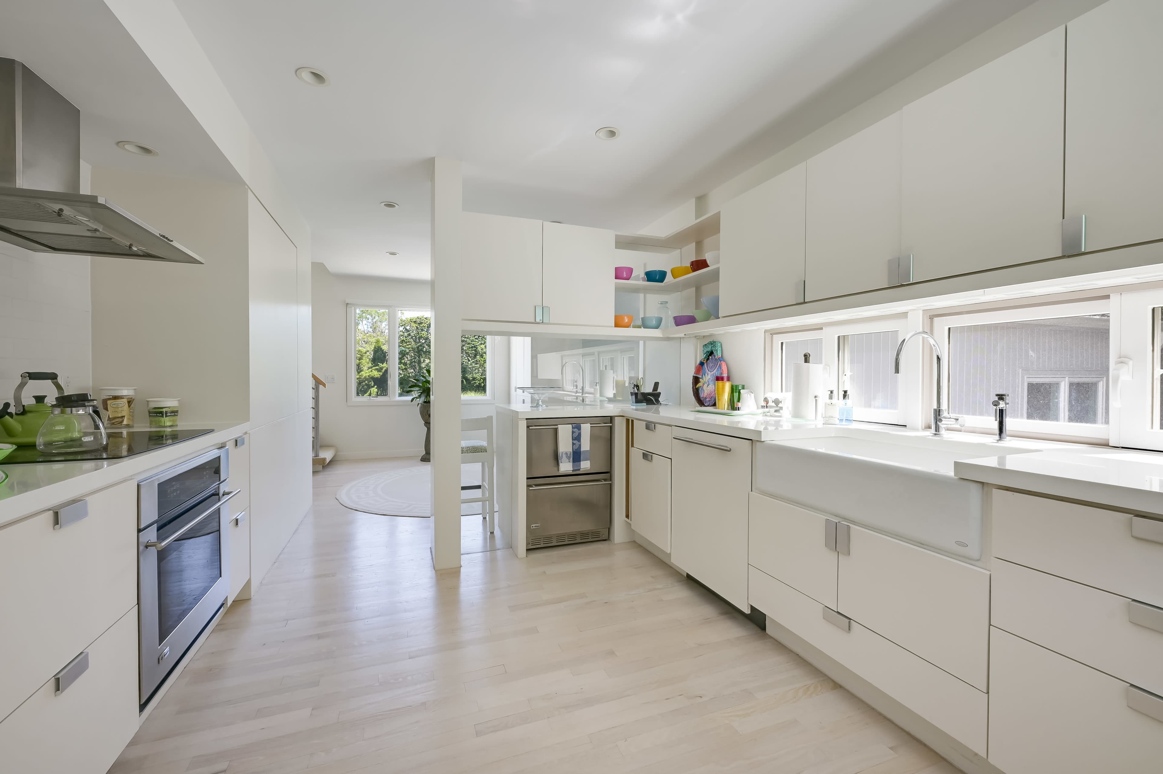 A modern kitchen with white cabinetry, a central island, and large windows that provide natural light.