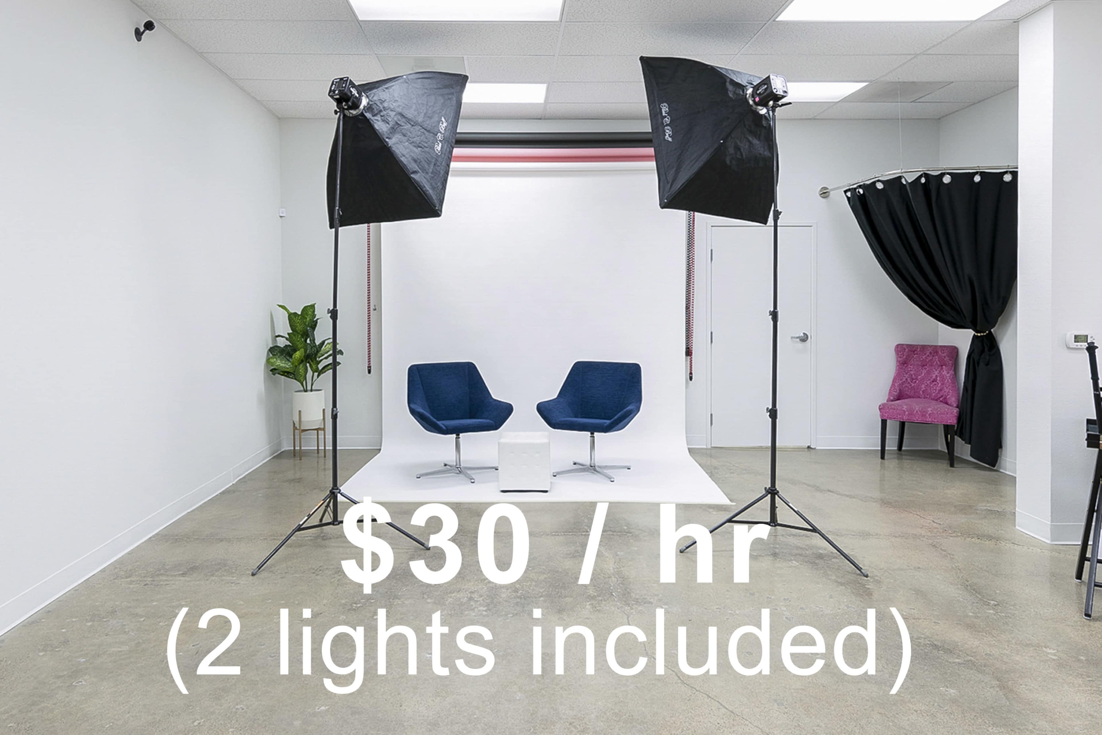 The image shows a photography studio with two blue chairs, two lighting setups, and a pink chair in a corner, all within a white room.
