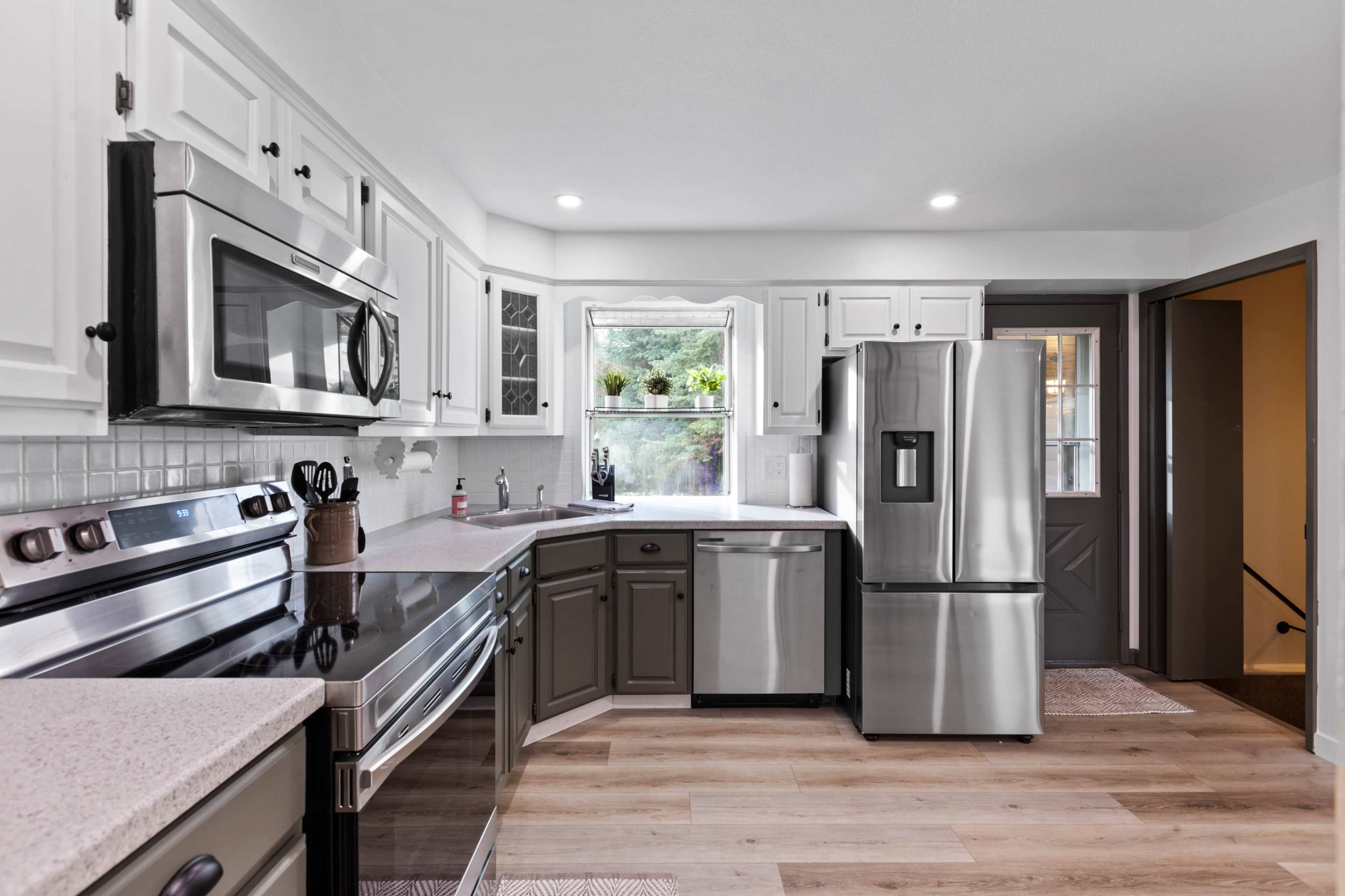 A modern kitchen featuring stainless steel appliances, white cabinets, and a dark countertop.