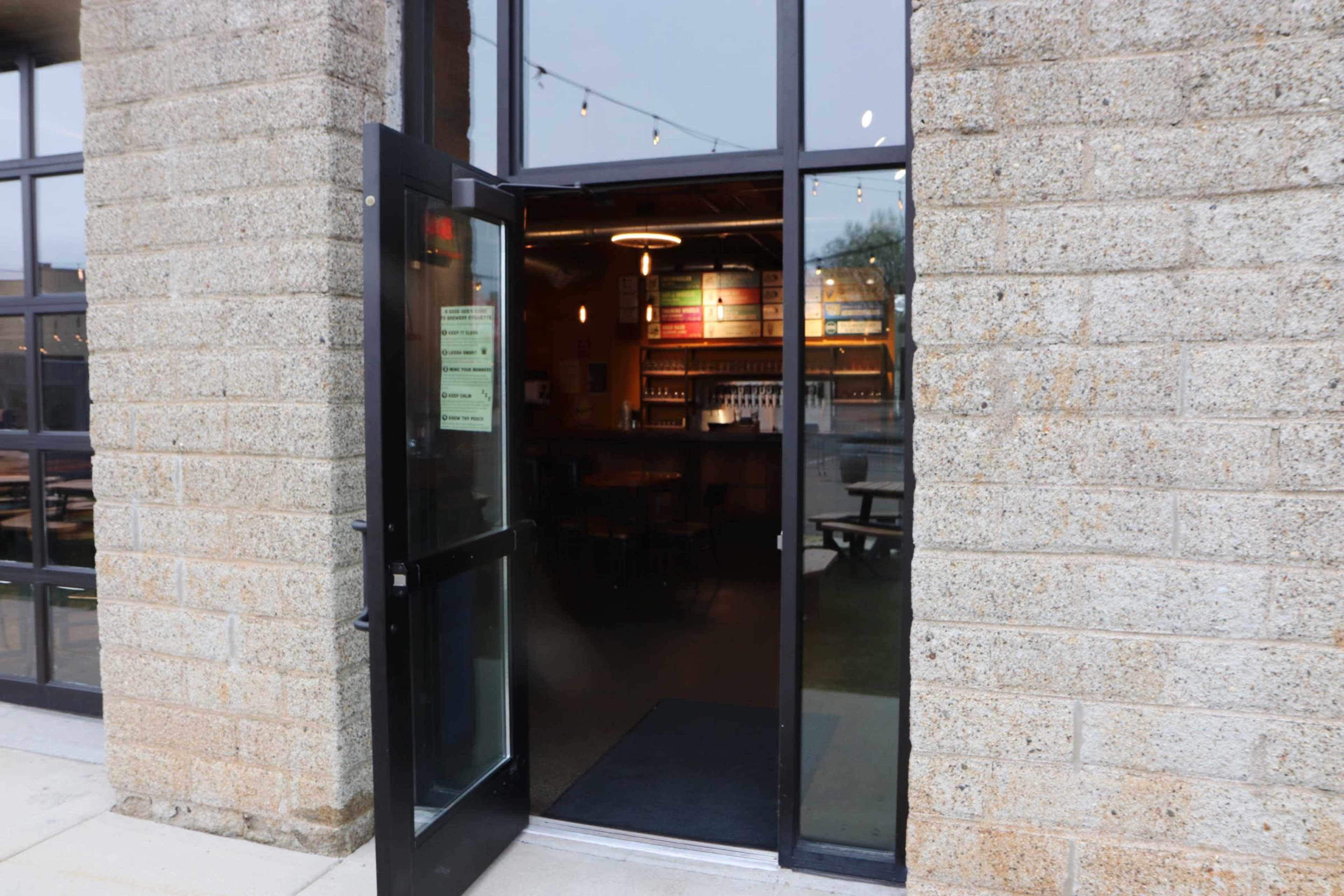 An open doorway leading into a well-lit interior of a restaurant with shelves and seating visible inside.