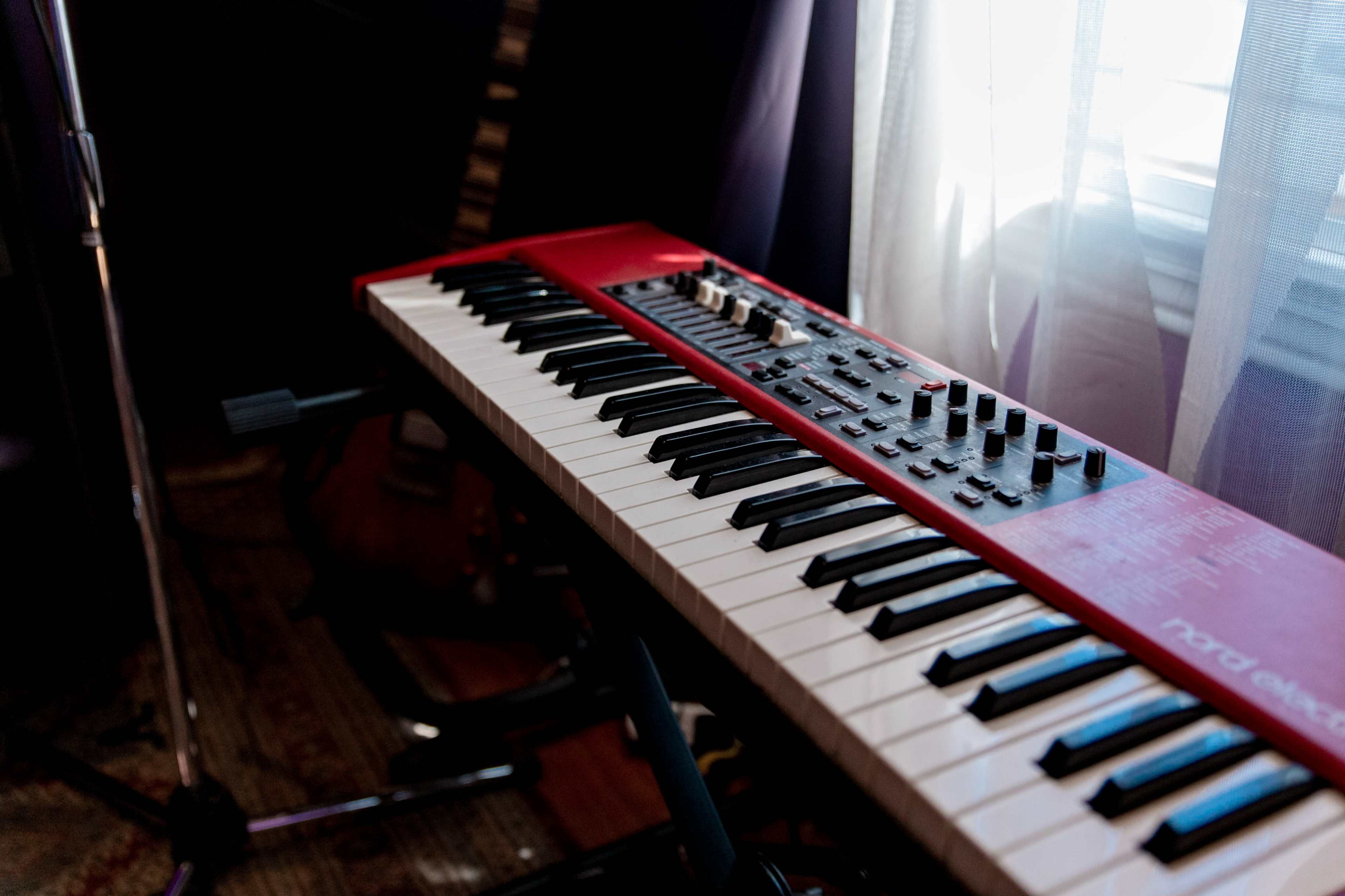 A red keyboard with black and white keys sits near a window, illuminated by natural light.