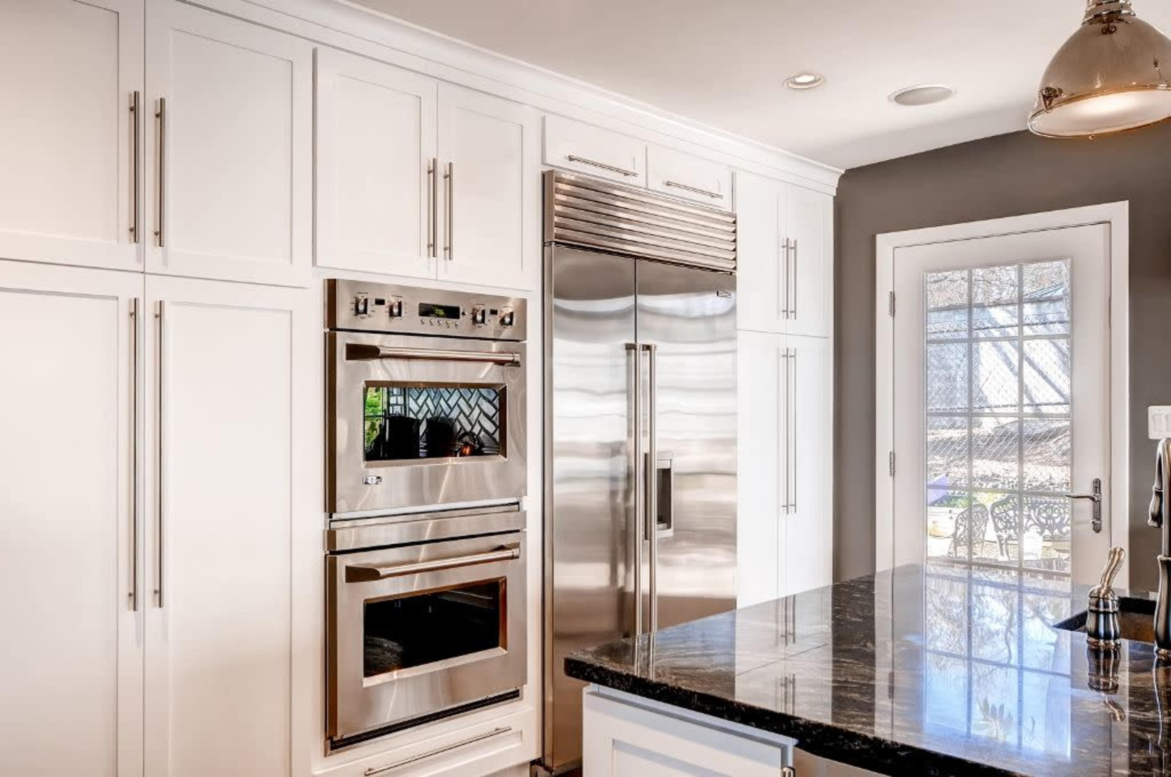 A modern kitchen with stainless steel appliances, including an oven and refrigerator, and a black countertop.